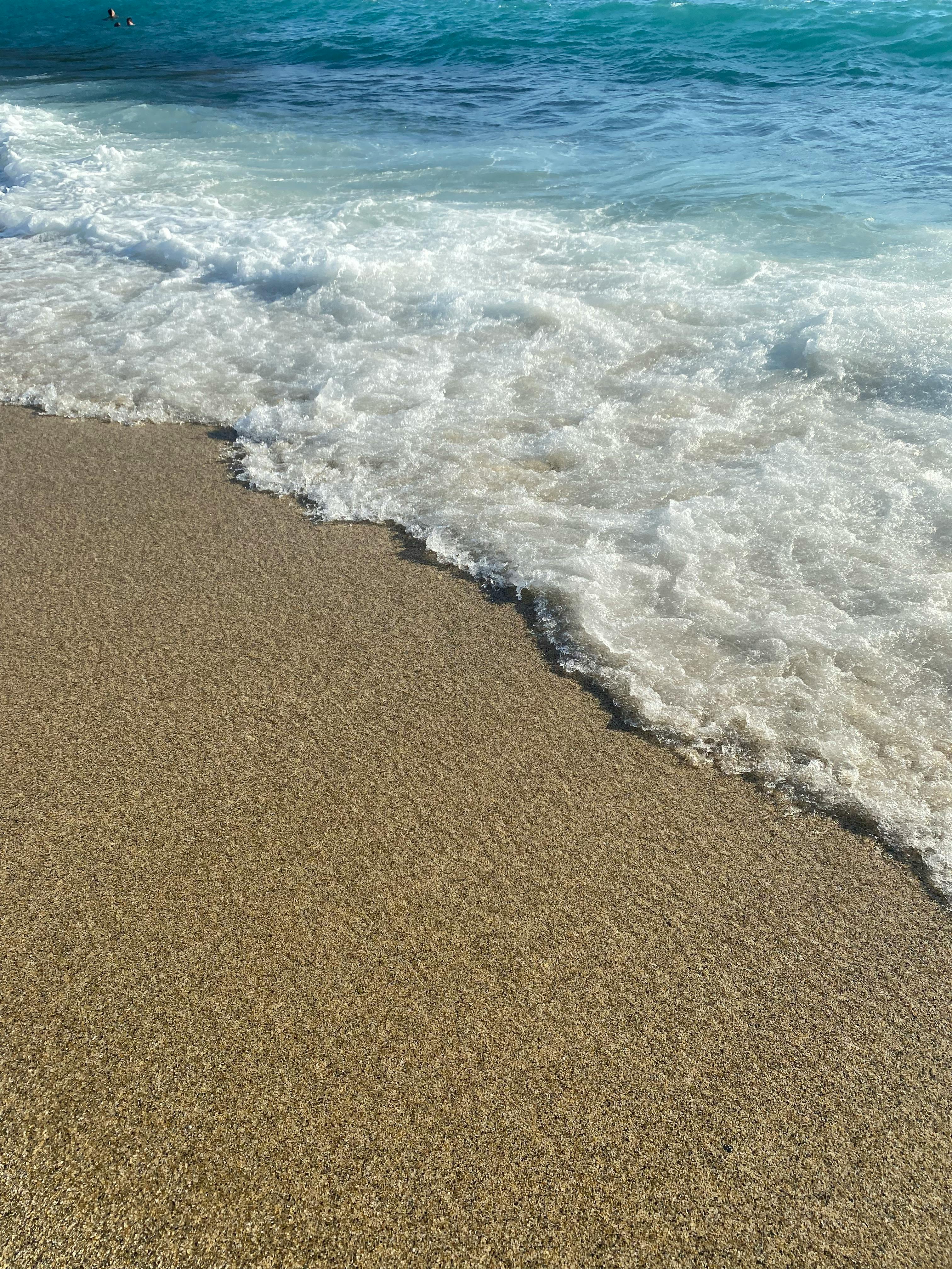 Gratis Rolige havbølger som skyller forsiktig over sandstranden i rolige kystomgivelser. Arkivbilde