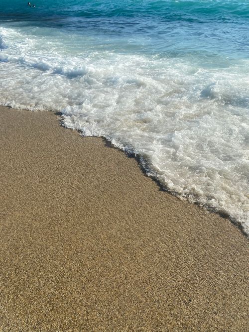 Free Calm ocean waves gently washing over the sandy beach in a serene coastal setting. Stock Photo