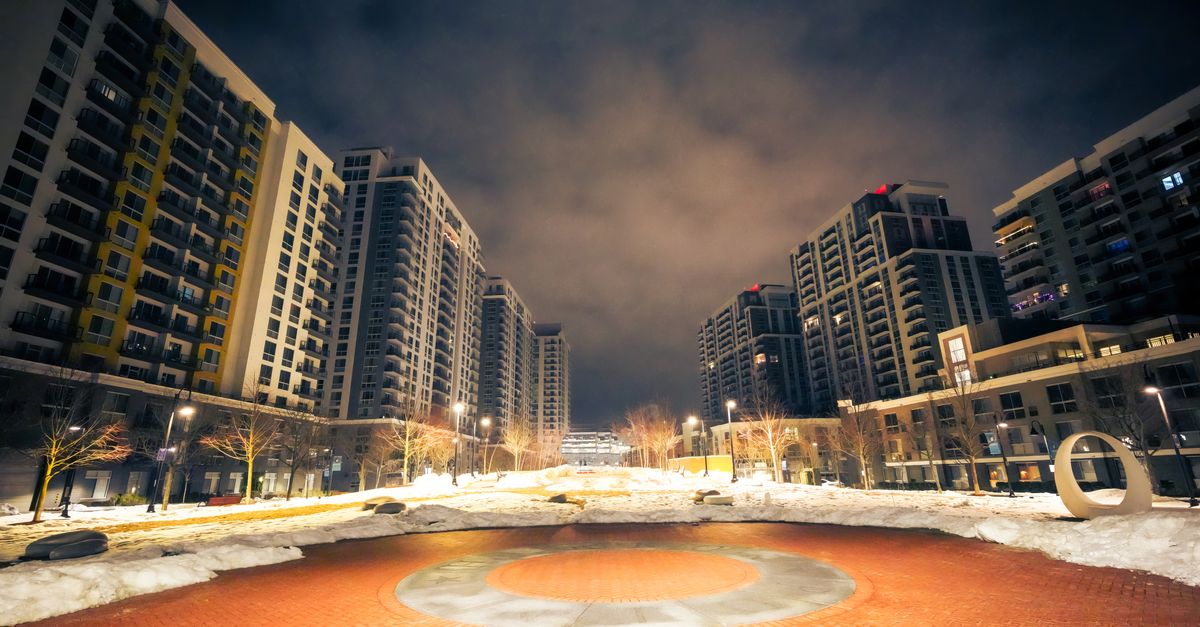 City night scene featuring tall residential buildings with a plaza, captured in winter.