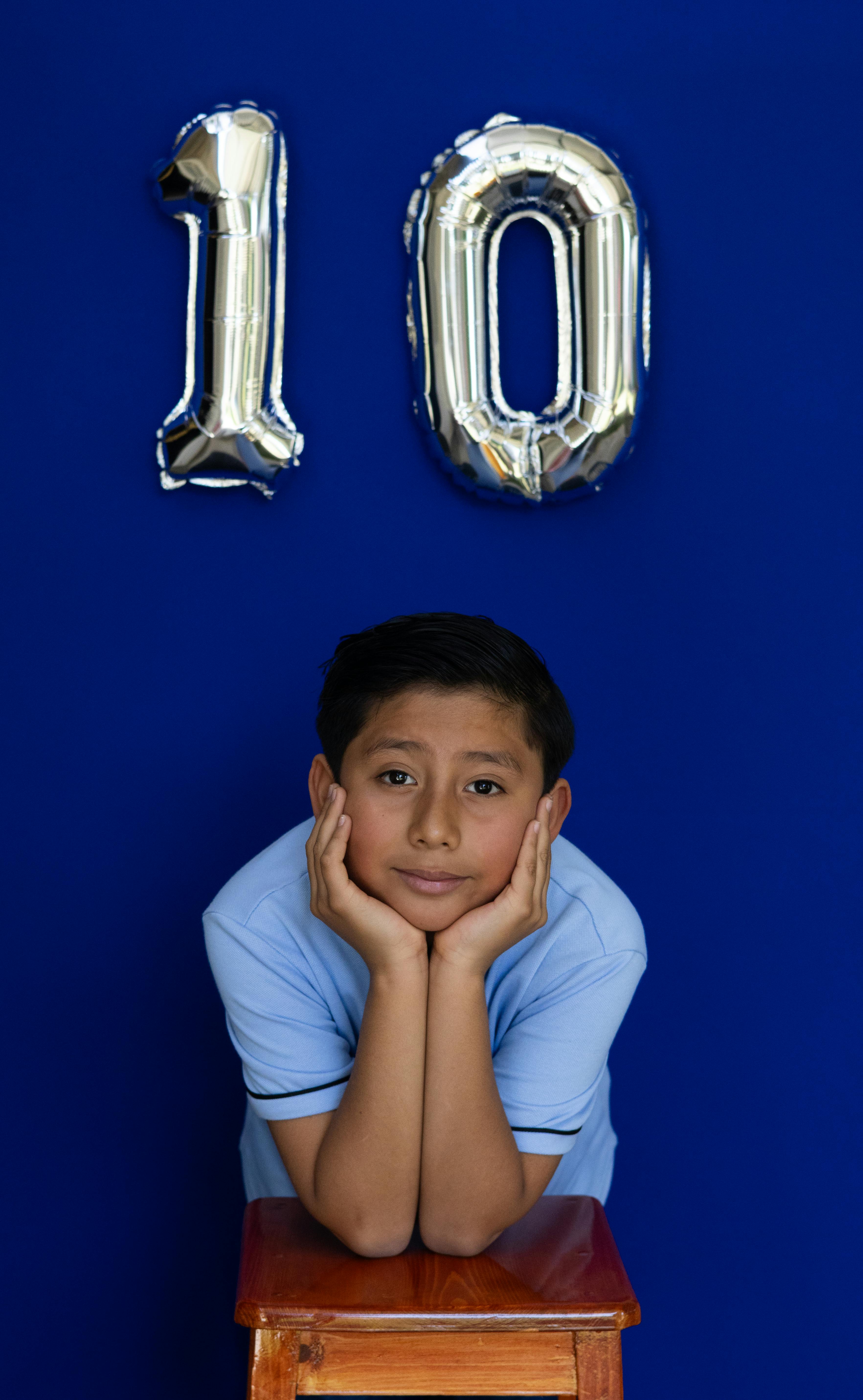 無料 10個の風船を持ってポーズをとる男の子。室内で誕生日を祝っています。活気に満ちた楽しい雰囲気です。 写真素材