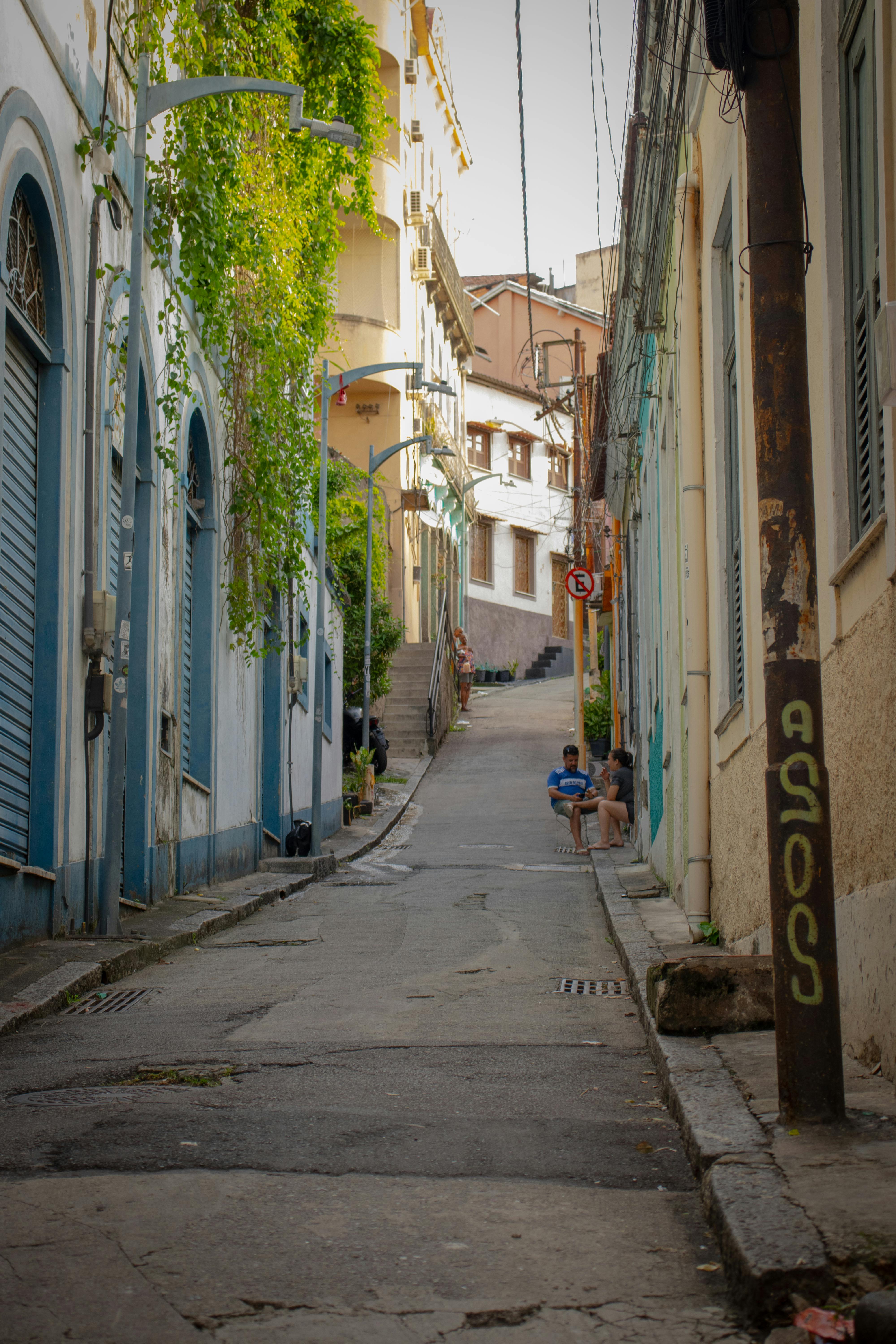 Gratis Malerisk gateutsikt i Santa Teresa, Rio med fargerike bygninger, grøntområder og lokalbefolkningen. Arkivbilde