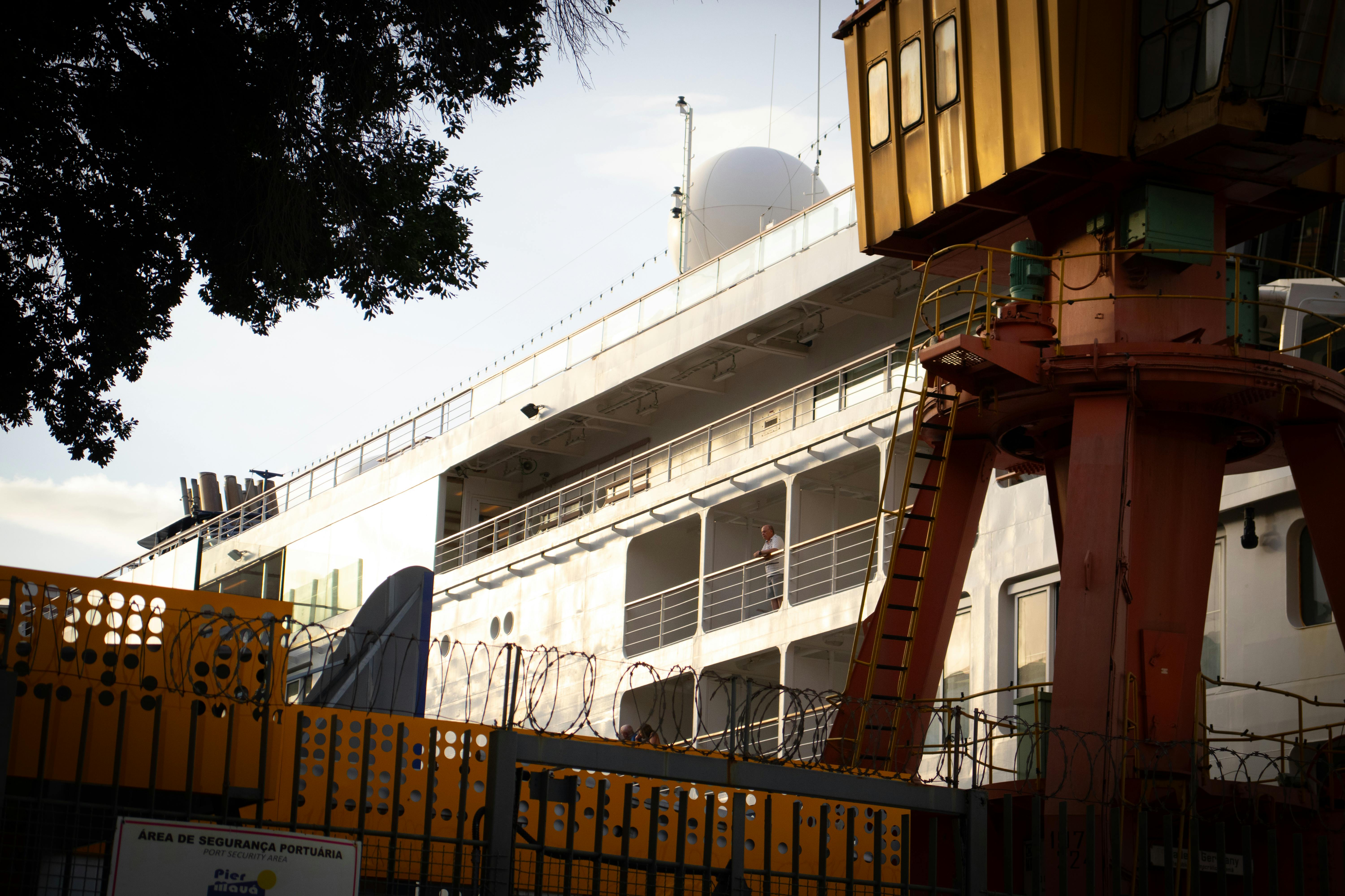 無料 安全柵と産業用クレーンが設置されたクルーズ船がリオの港に停泊している。 写真素材