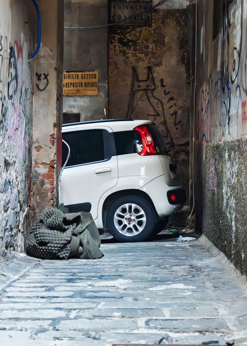 Gratis Auto bianca stretta in un vicolo stretto con muri ricoperti di graffiti. Foto a disposizione