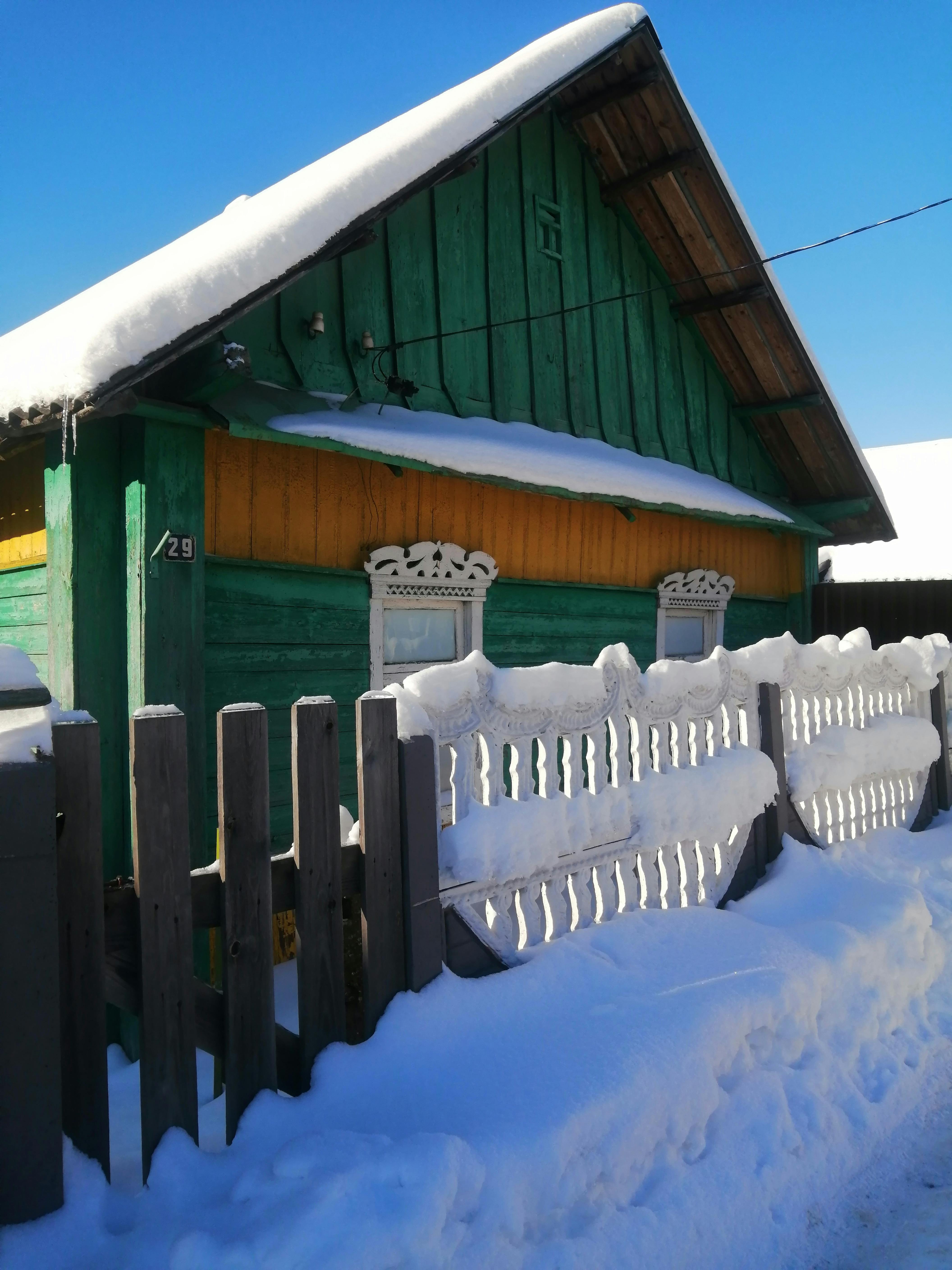 無料 明るい冬の日に雪に覆われた活気のある素朴な家。 写真素材