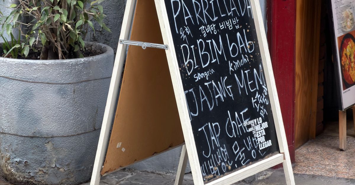 A street-side chalkboard menu with international dishes in Barcelona, Spain.