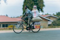 Man balancing goods on bicycle in urban setting