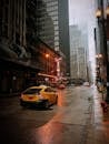 芝加哥市中心一条多雨的街道上，一辆黄色的出租车在高耸的摩天大楼间穿行