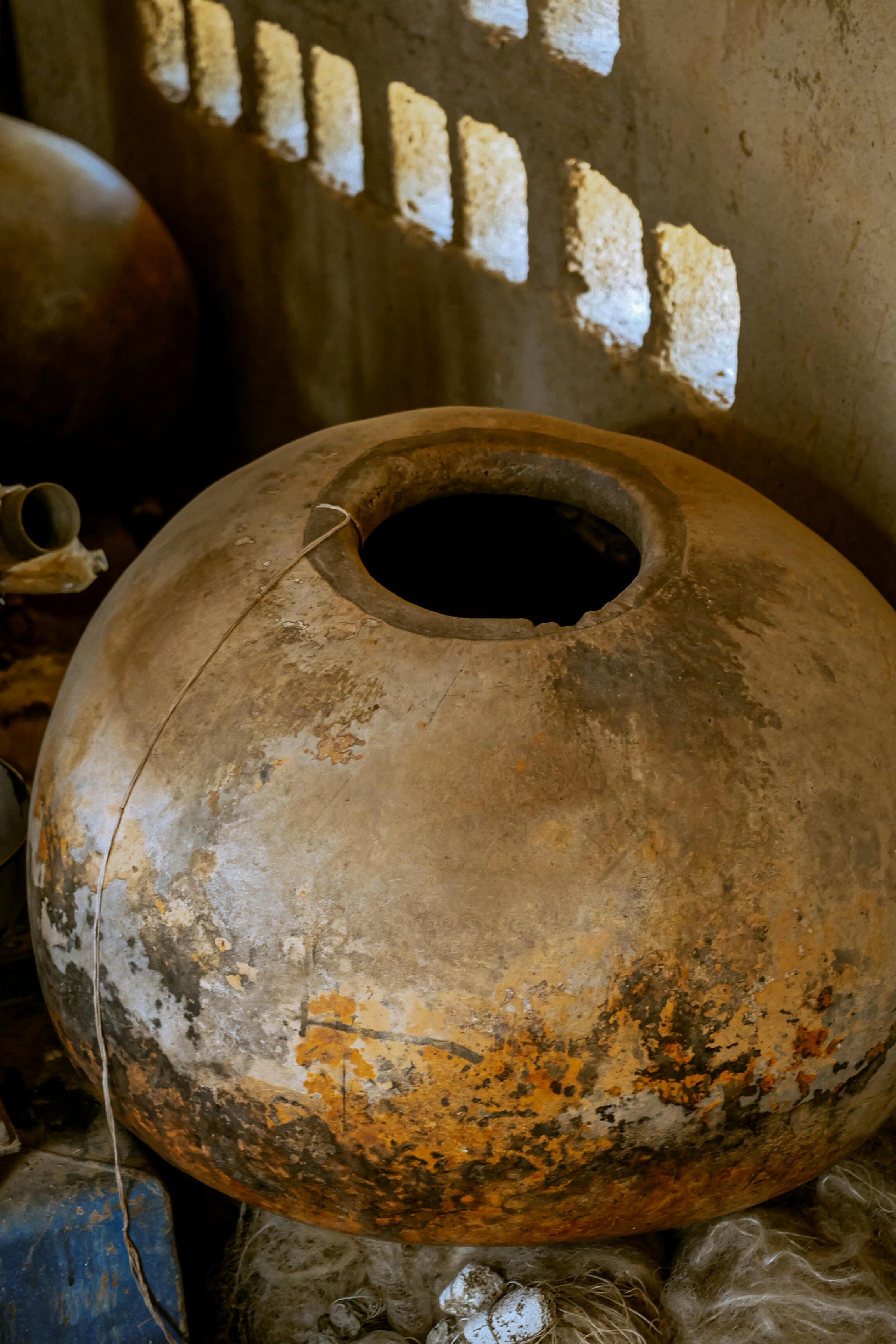 無料 窓から自然光が差し込む雰囲気のある室内に、風化した土鍋が置かれています。 写真素材