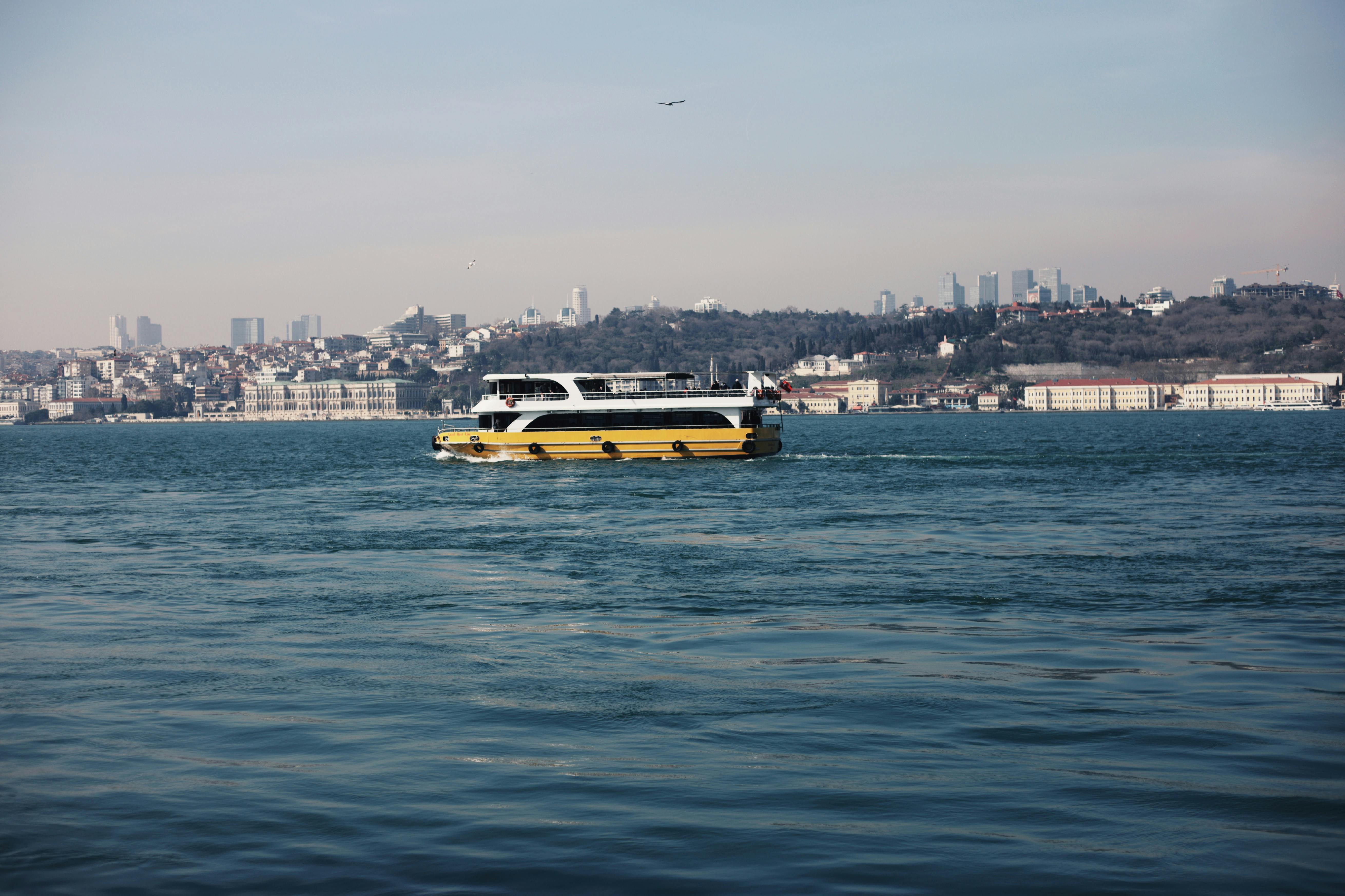 Gratuit Un ferry naviguant sur le Bosphore, avec la silhouette d'Istanbul en arrière-plan sous un ciel dégagé. Photos