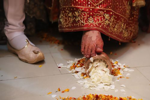 Free A bride performs a traditional Indian wedding ceremony ritual involving flower petals on the floor. Stock Photo