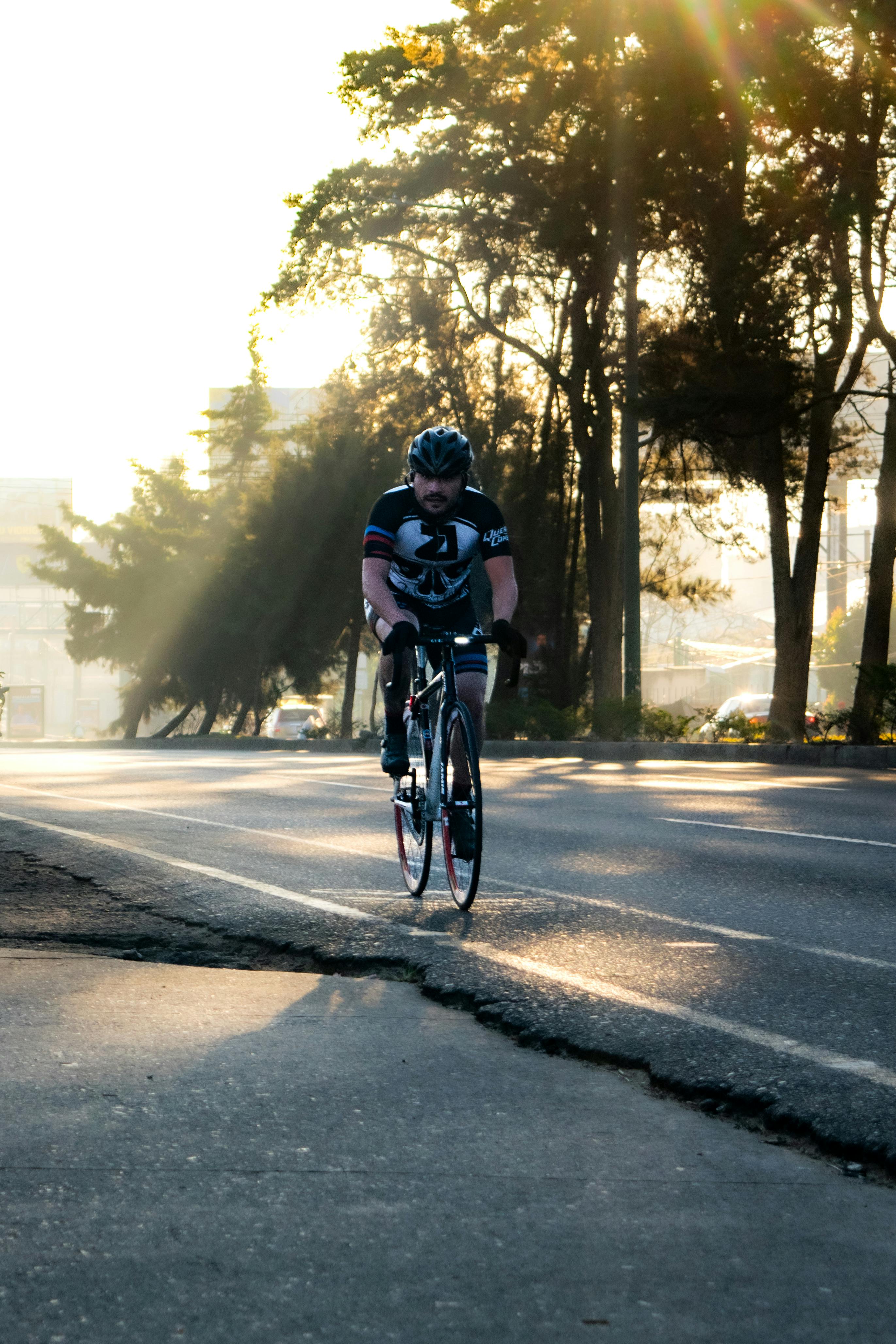 бесплатная Велосипедист на залитой солнцем дороге в городе Гватемала, запечатлевший утреннюю атмосферу. Стоковое фото
