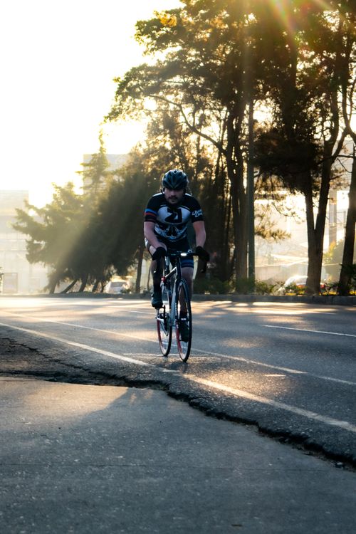 Free Cyclist on a sunlit road in Ciudad de Guatemala, showcasing the morning ambiance. Stock Photo