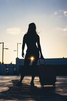 Silhouette of a woman with a suitcase during sunset in Miami. Captures the essence of travel and adventure.