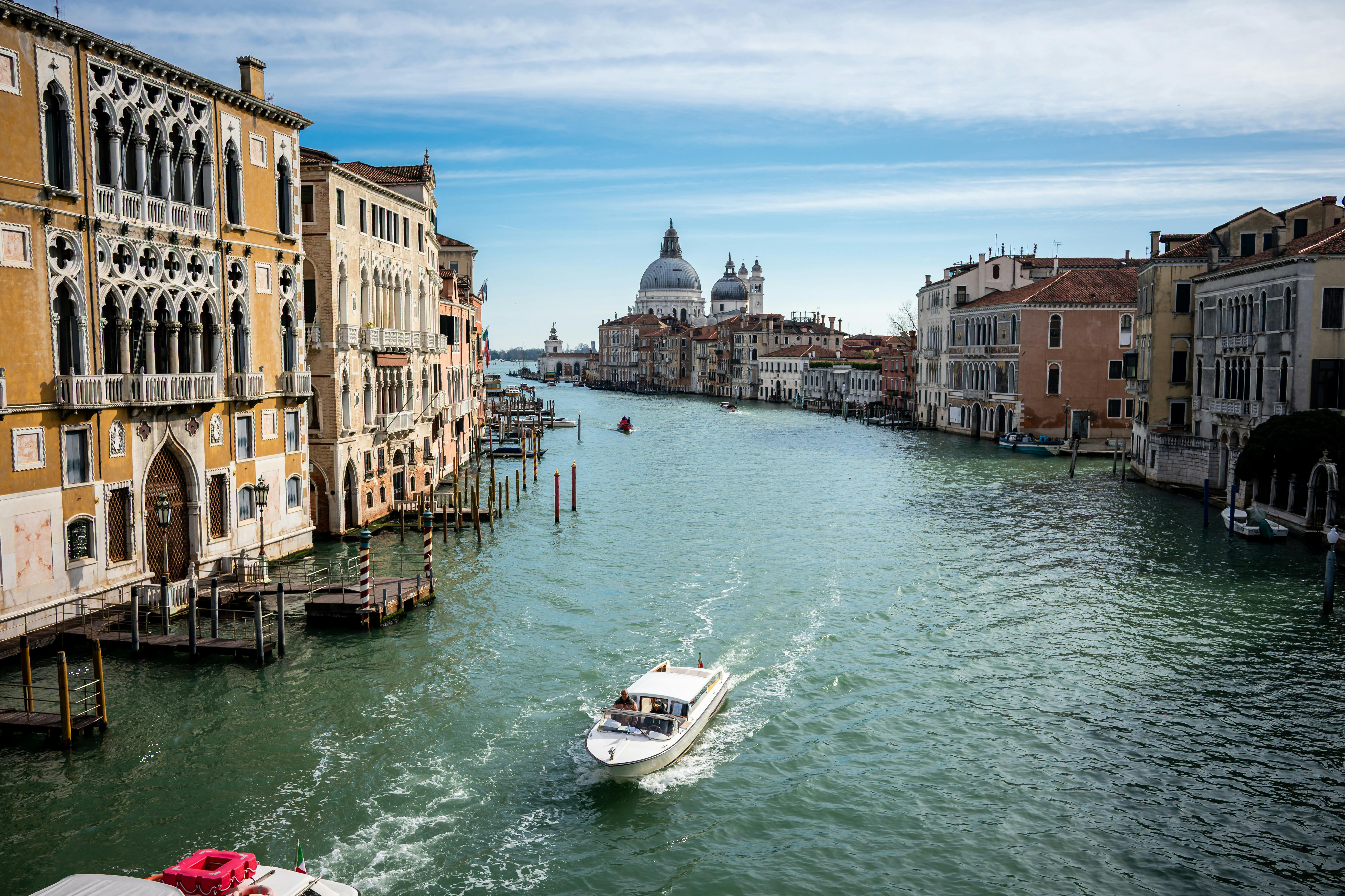 無料 歴史的な建築物とサンタ・マリア・デッラ・サルーテ教会のあるヴェネツィアの大運河を行く船の静かな眺め。 写真素材