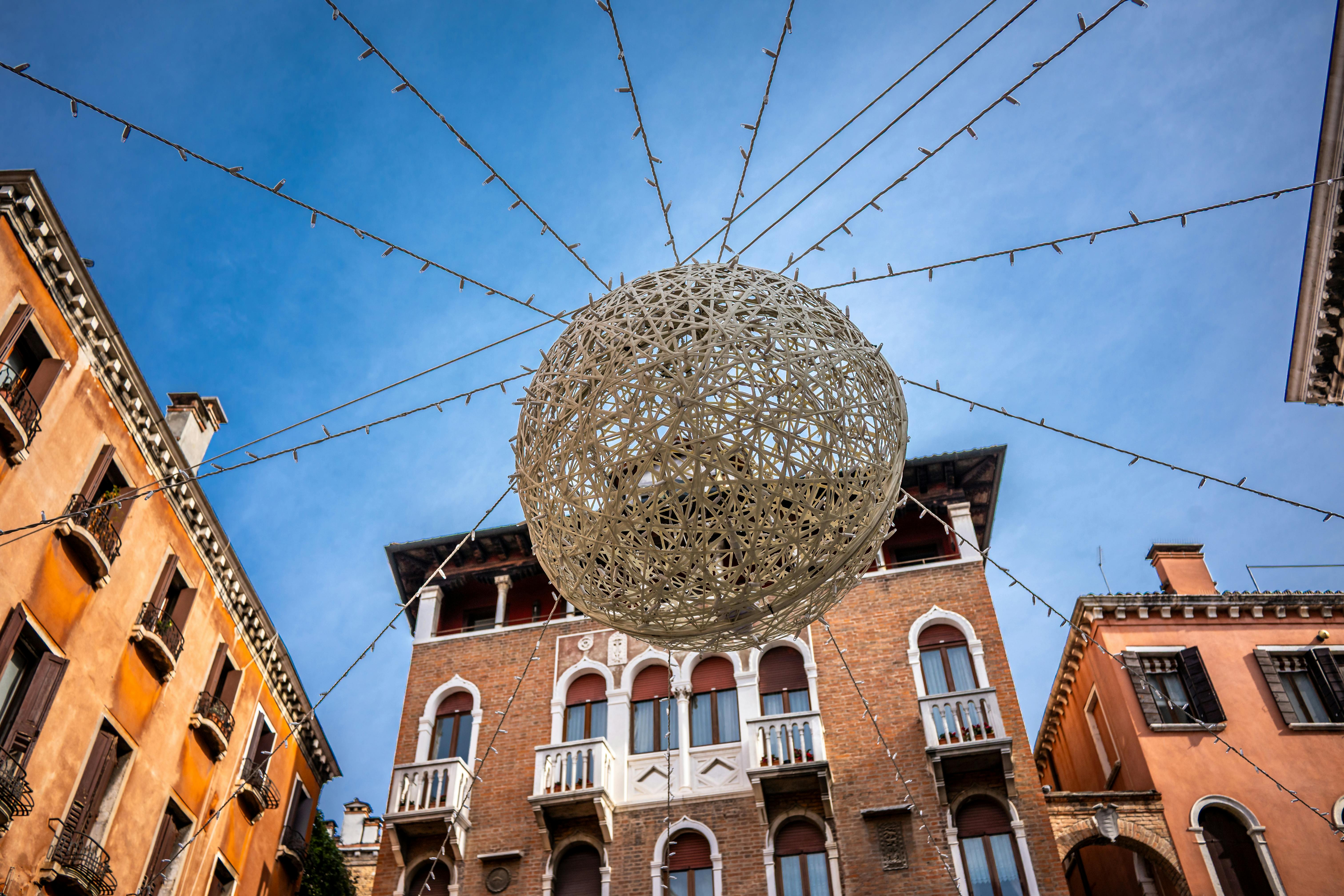 無料 晴れた空の下のベネチアの建物の上にライトが付いた装飾的な球体。 写真素材
