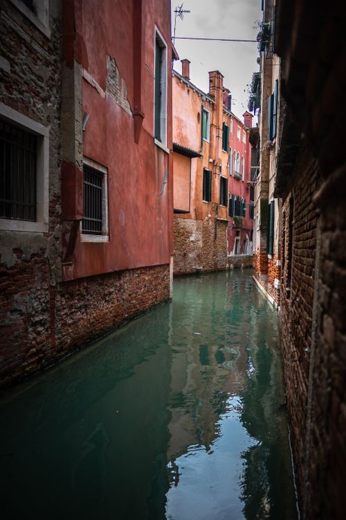 Free View of a narrow canal in Venice surrounded by historic buildings. Stock Photo