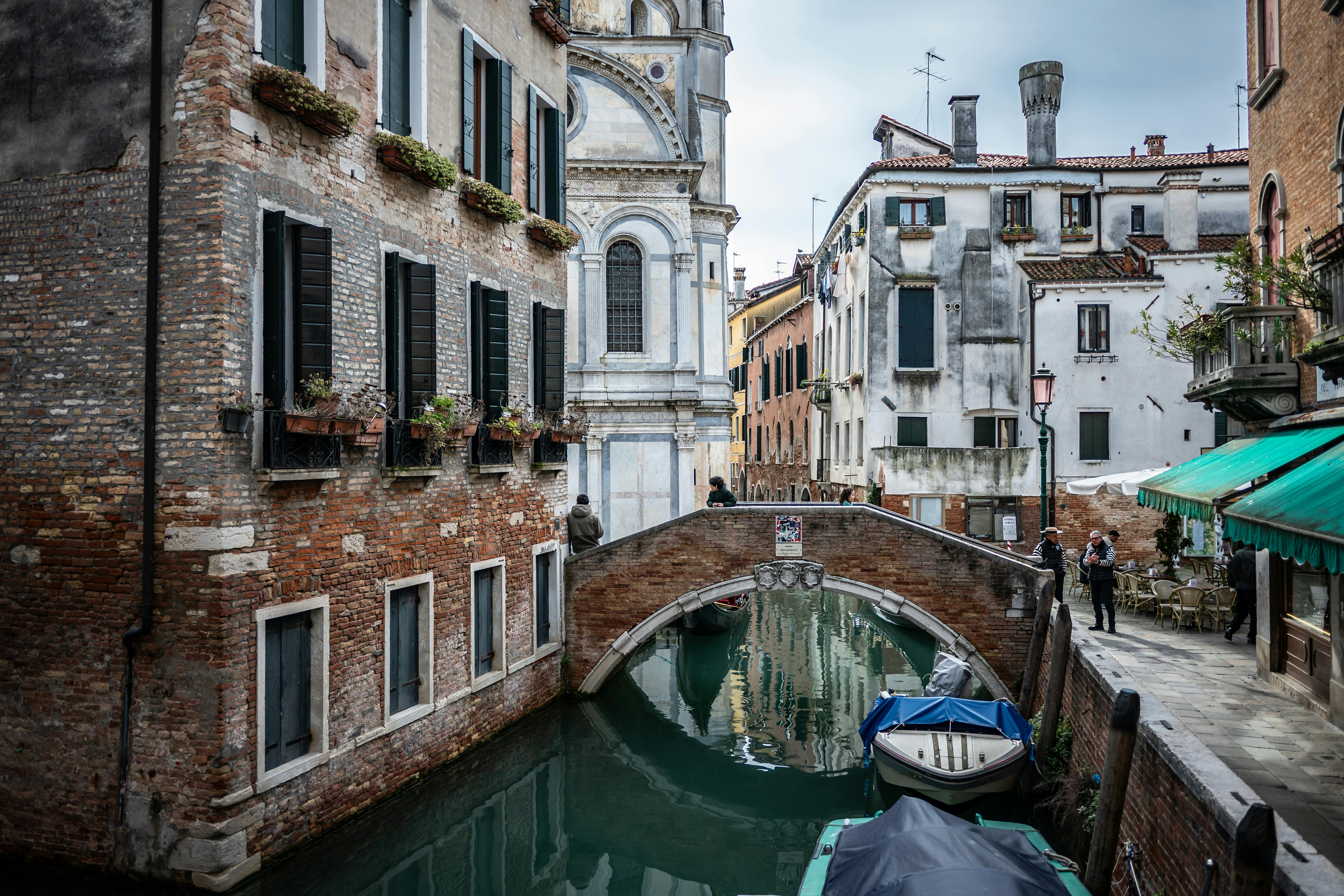 無料 イタリアのベネチアにある、古典的な建築と静かな橋が特徴的な美しいベネチアの運河の風景。 写真素材