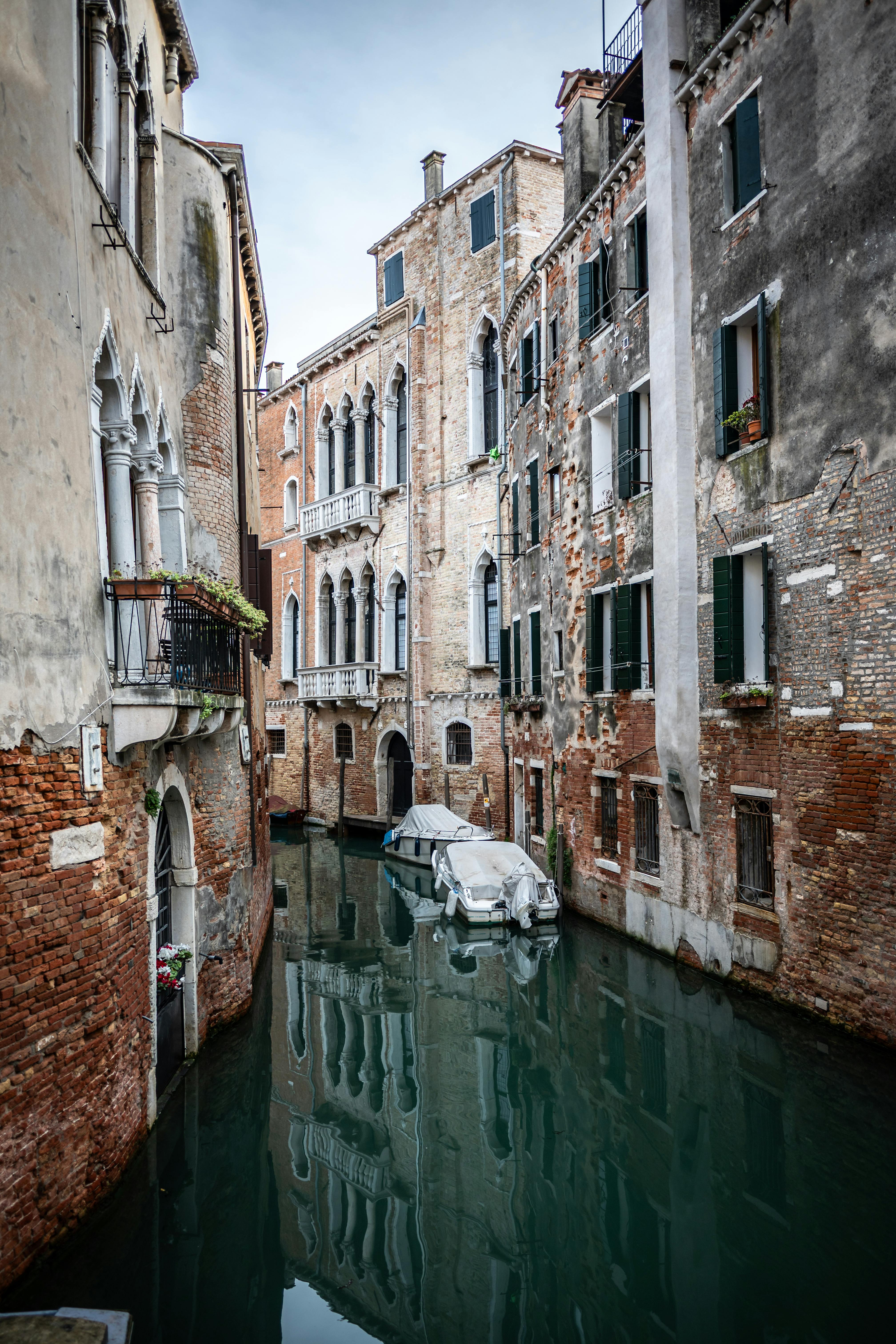 無料 歴史的なベネチア建築が水面に映る静かな運河の眺め。 写真素材