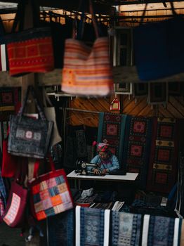 A vibrant scene of a traditional textile market in Lào Cai, showcasing handcrafted fabric and bags.