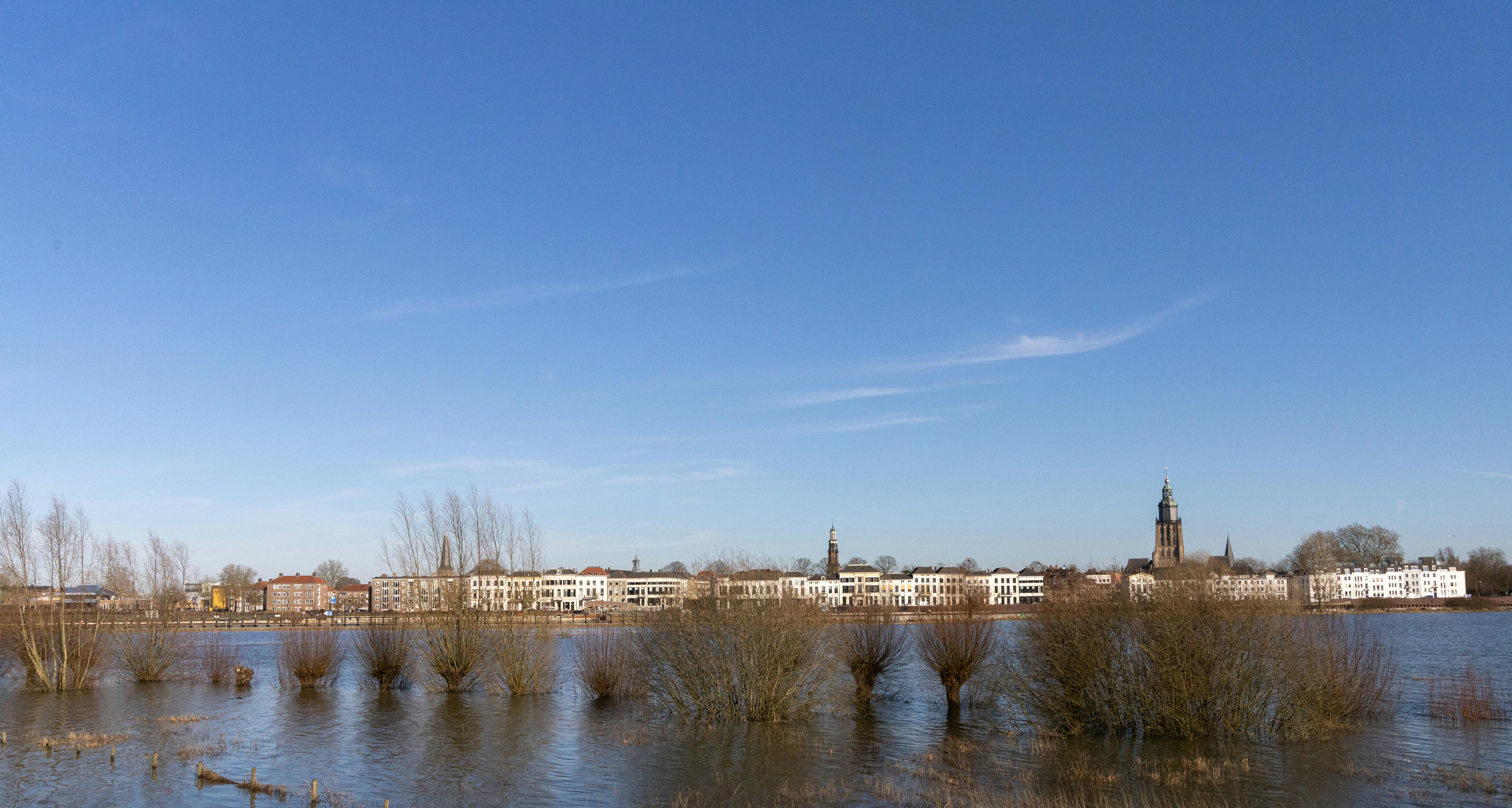 бесплатная Спокойный вид на панораму Зютфена с историческими зданиями и церковью у тихой реки. Стоковое фото