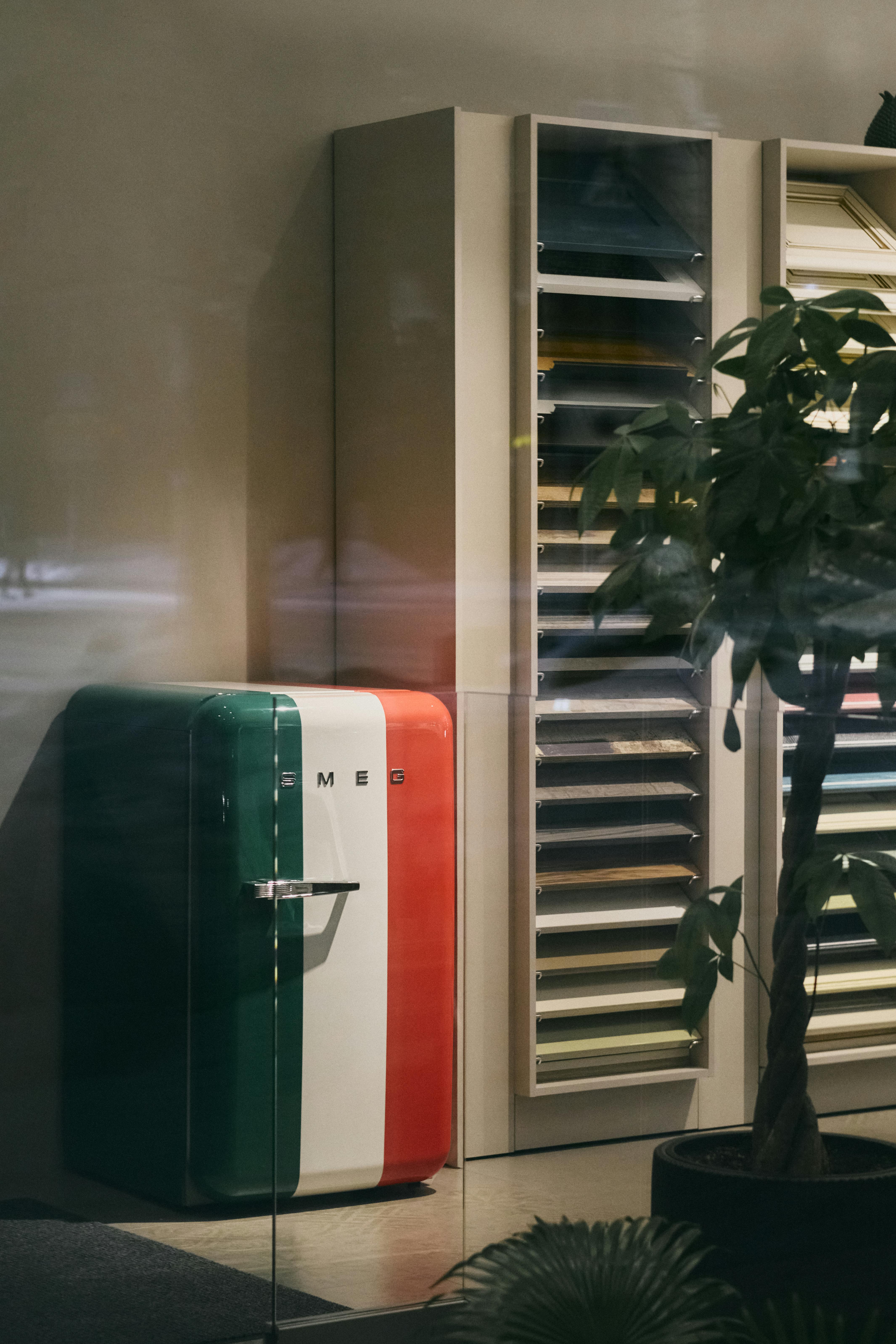Gratuit Un réfrigérateur tricolore de style vintage exposé dans un magasin de design avec des étagères modernes. Photos