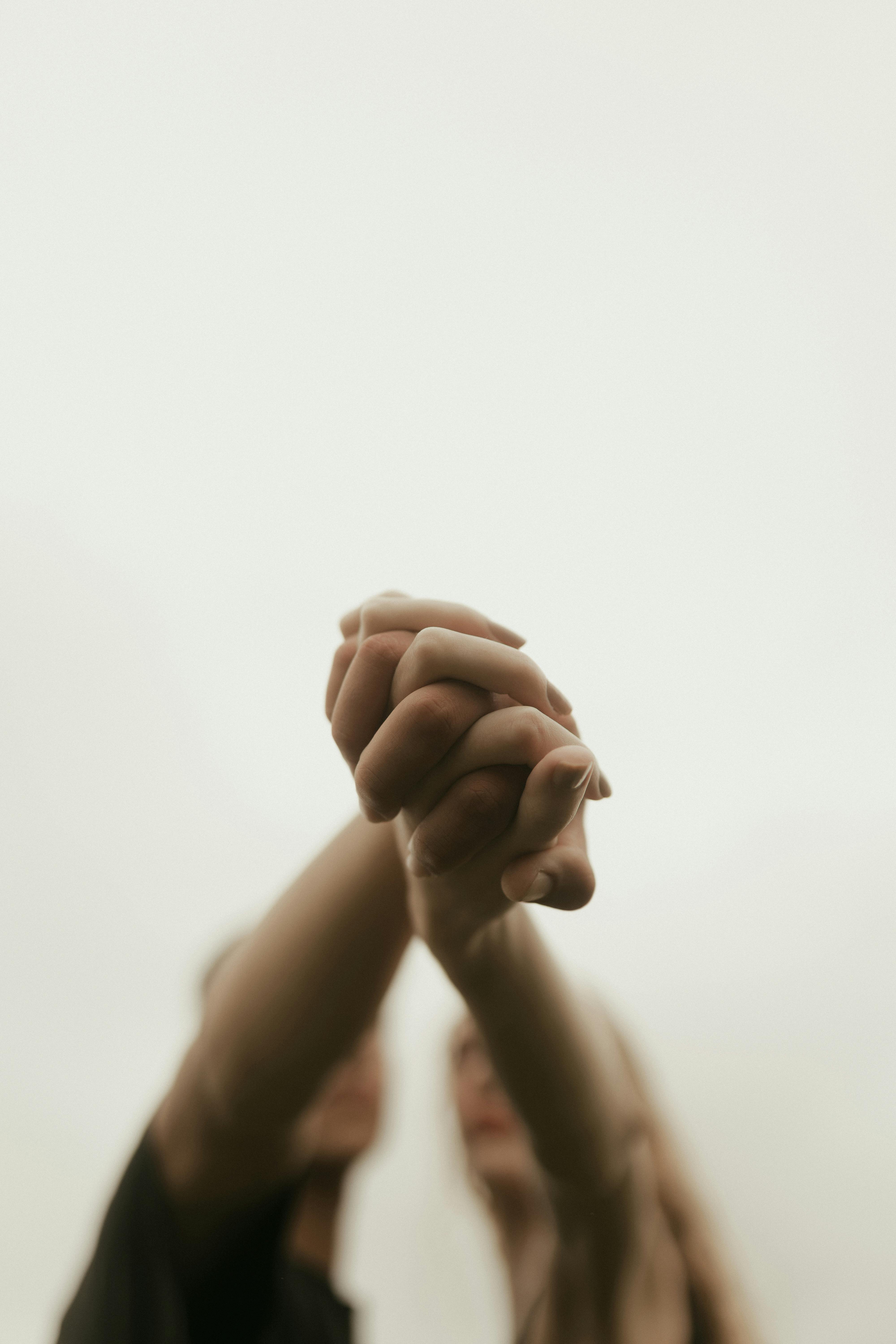 Free A minimalistic shot of interlocked hands symbolizing unity and connection against a soft background. Stock Photo