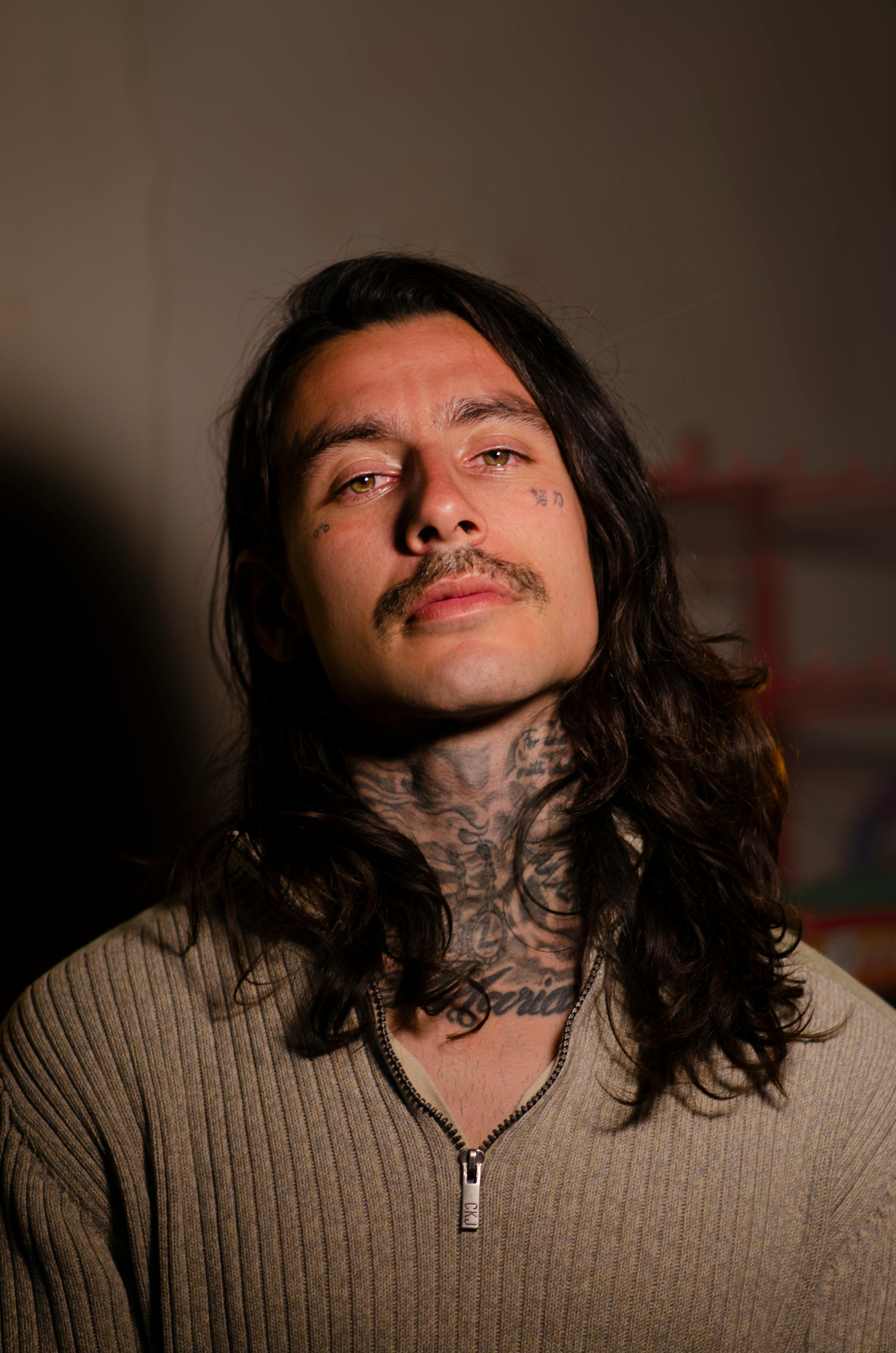 Free Moody portrait of a tattooed man wearing knitwear with long hair and mustache. Stock Photo