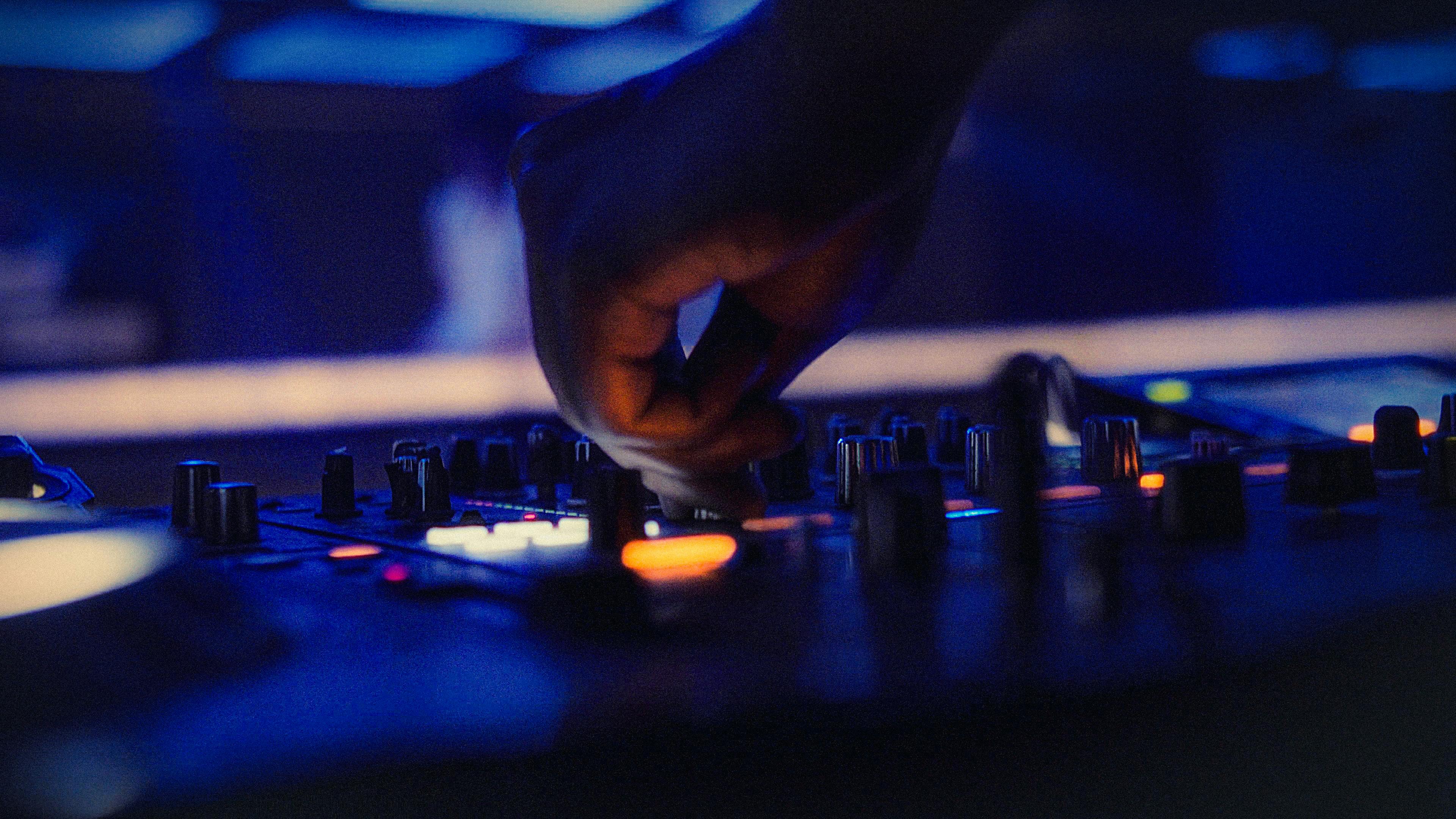 無料 活気のあるナイトクラブの雰囲気の中で、DJ がサウンド ミキサーのノブを調整しています。 写真素材