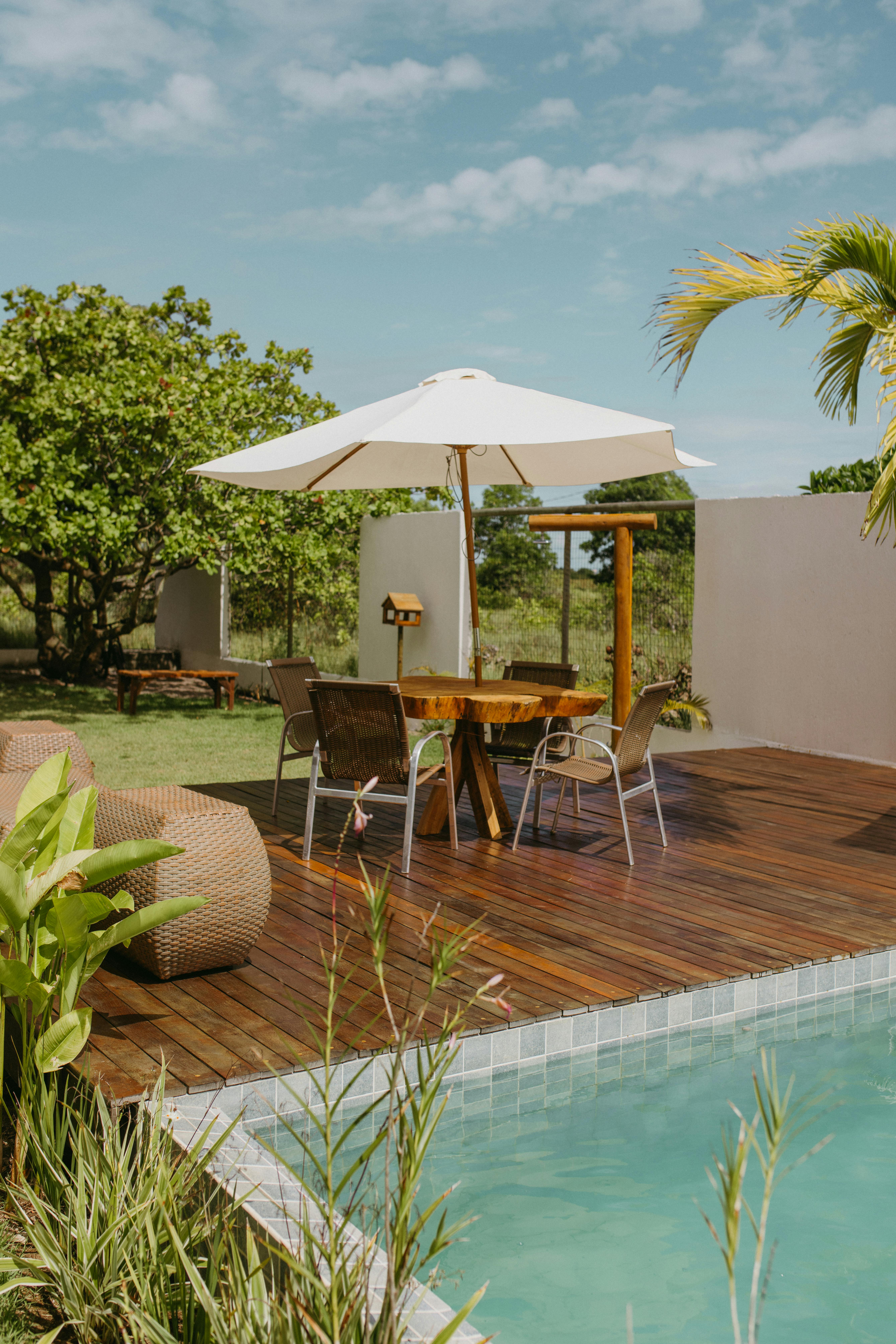 Free Sunny outdoor patio setup in Bahia, Brazil, featuring a wooden deck and poolside seating. Stock Photo