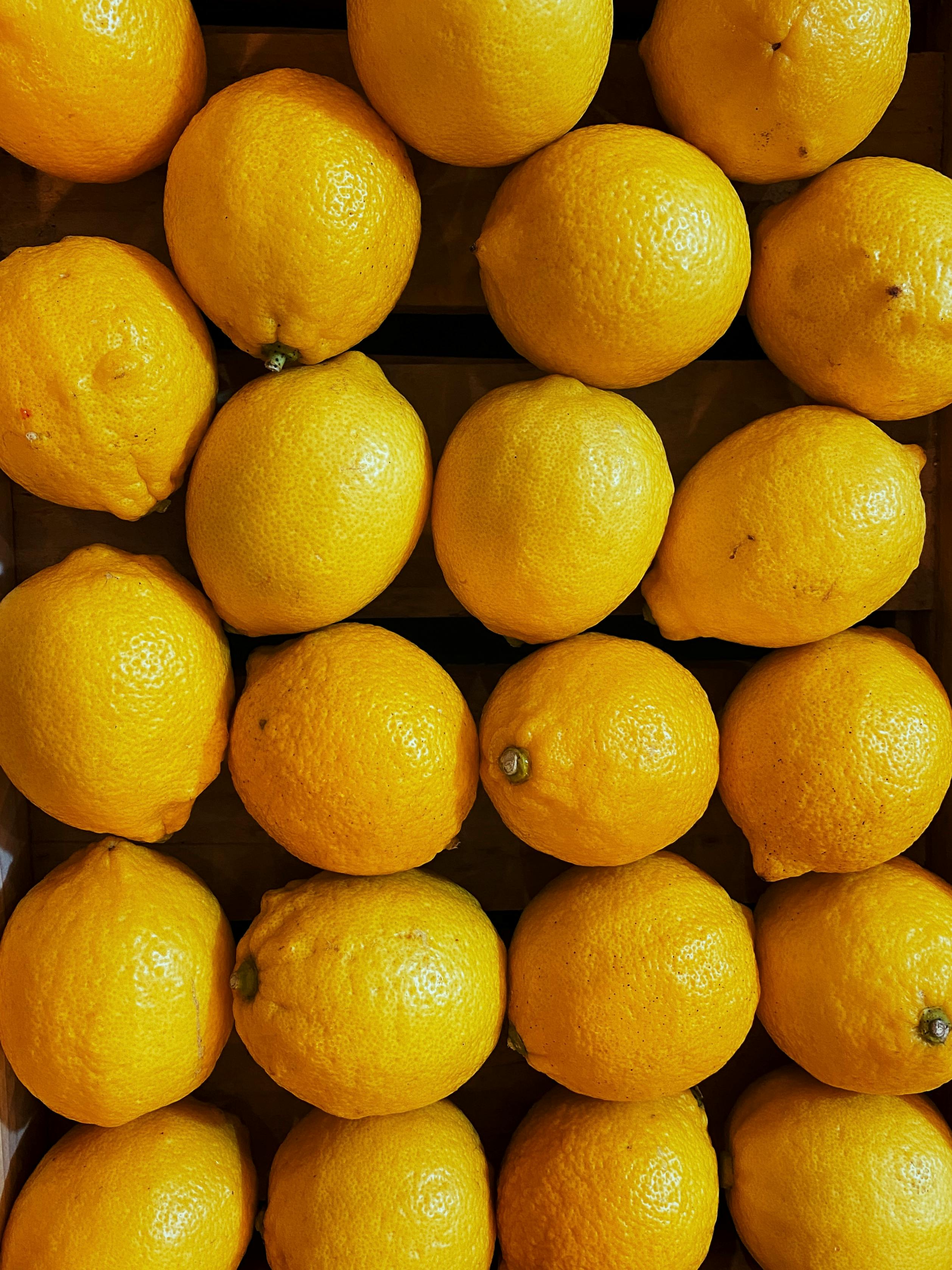 Free Bright yellow lemons arranged neatly in a grid pattern, creating a vibrant and fresh composition. Stock Photo