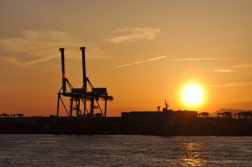 Free A striking silhouette of cranes at an industrial port during a vibrant sunset. Stock Photo