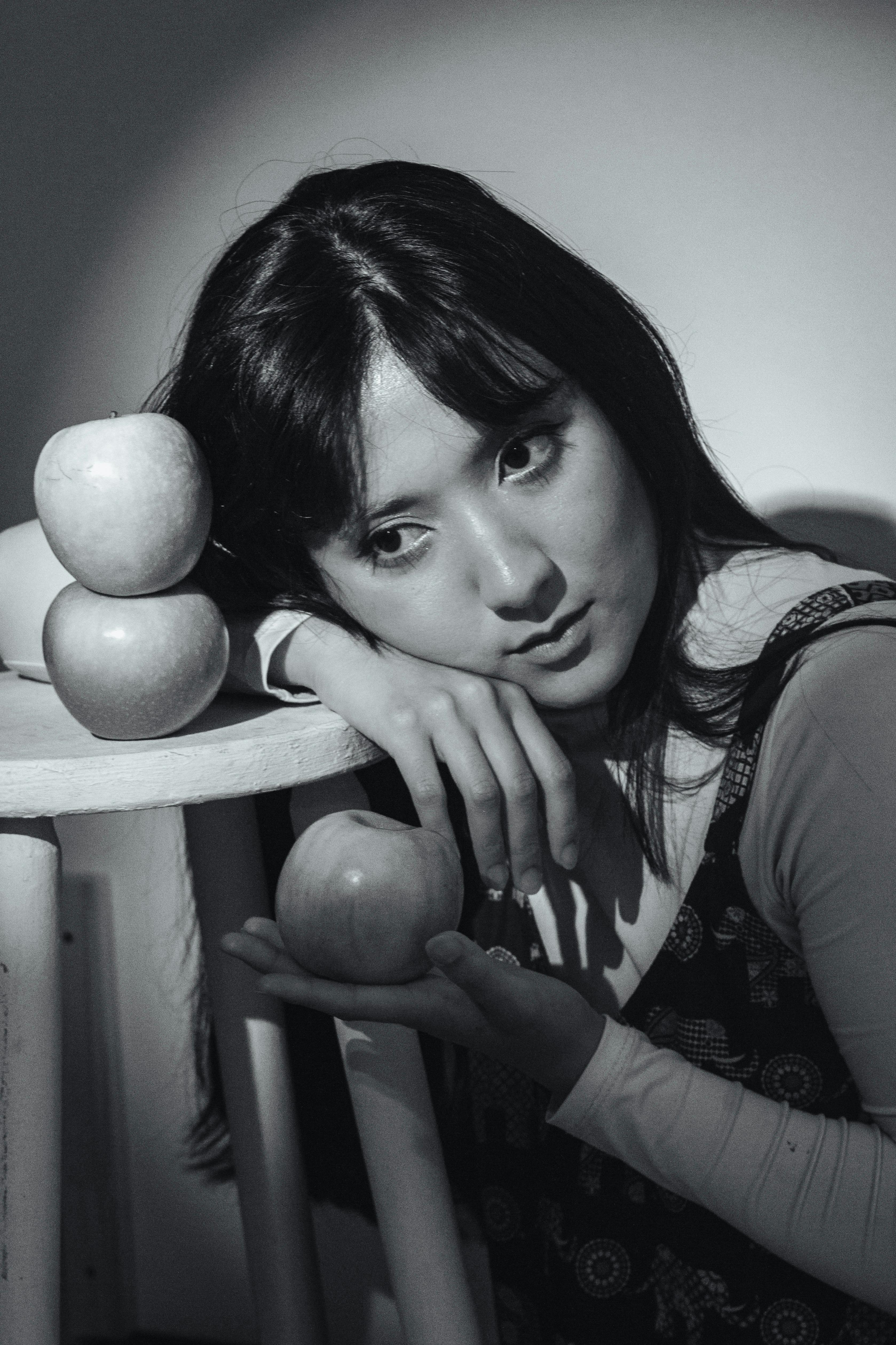 Free A thoughtful black and white portrait of a woman with apples, creating a moody artistic atmosphere. Stock Photo