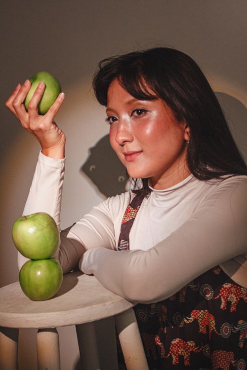 Free Young woman with apples posing indoors, stylish and vibrant. Stock Photo