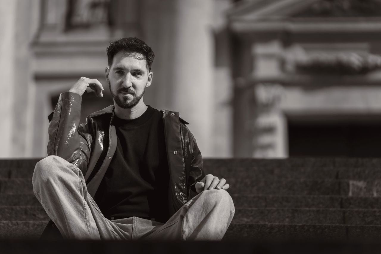 stylish black and white portrait of a man sitting outdoors expressing