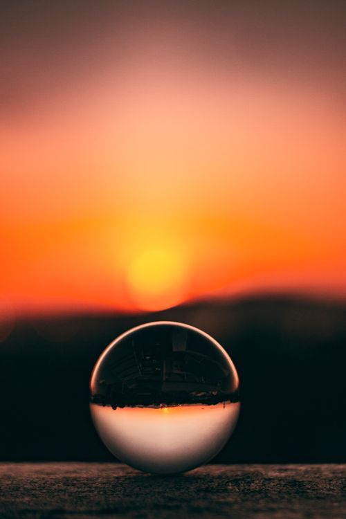 Free Stunning sunset captured in a reflective crystal ball with glowing orange and red sky. Stock Photo