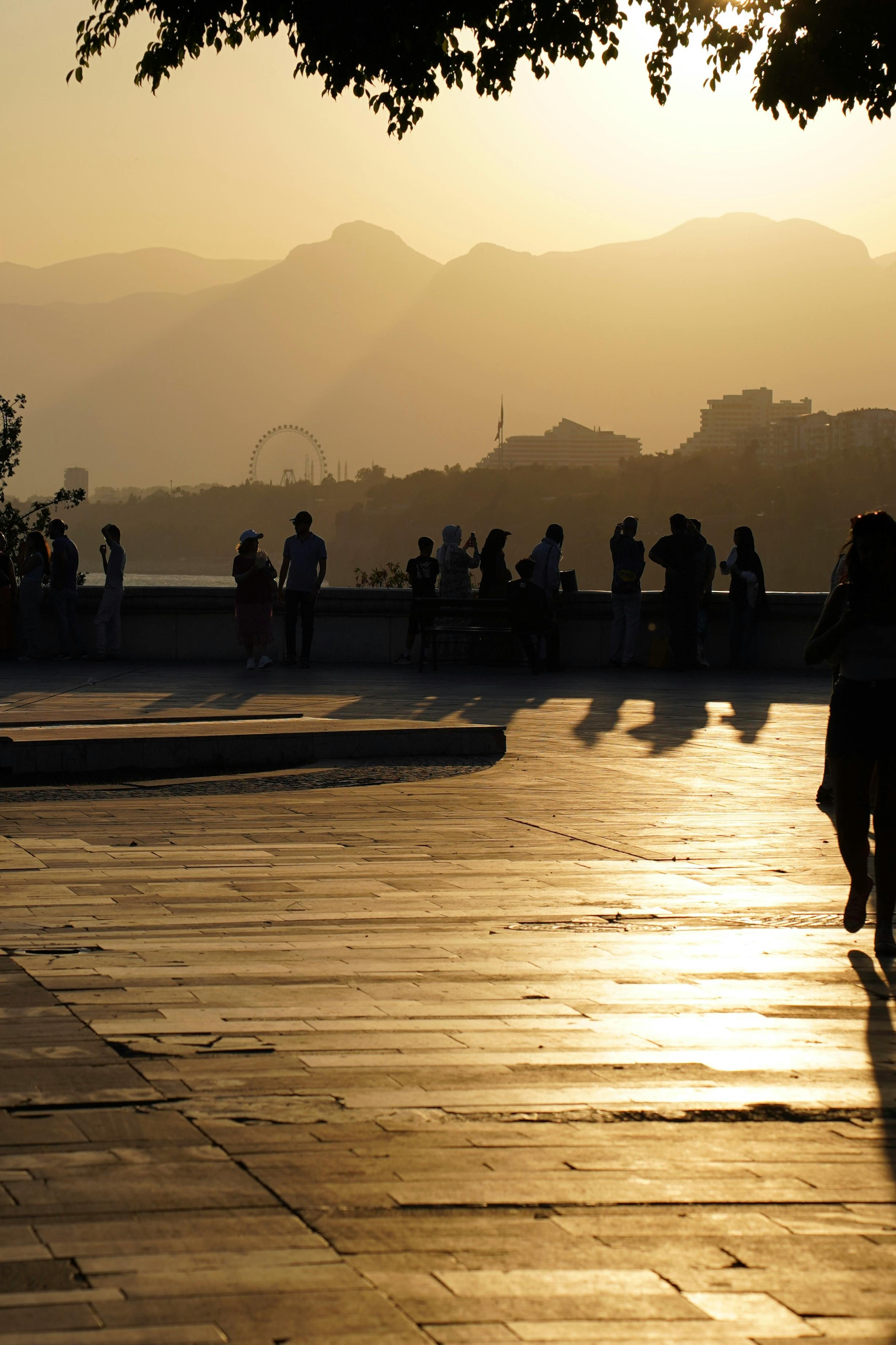 Free People enjoy the golden sunset view over the mountains and cityscape of Antalya. Stock Photo