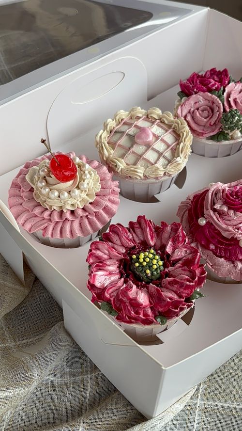 Free Decorative floral cupcakes with intricate icing designs in a box, perfect for celebrations. Stock Photo