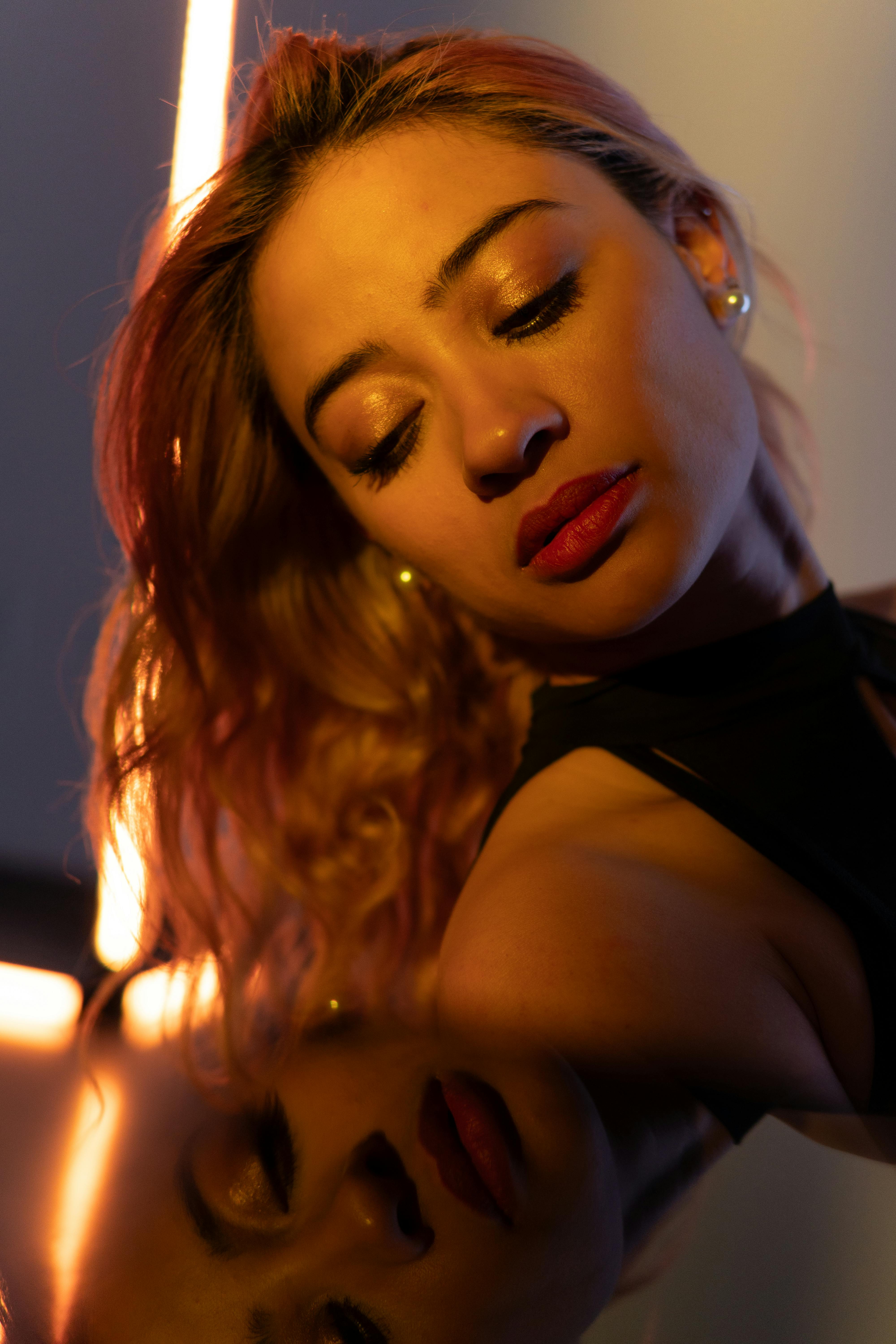 無料 暖かい照明の下でドラマチックに映る、魅惑的な女性のポートレート。 写真素材