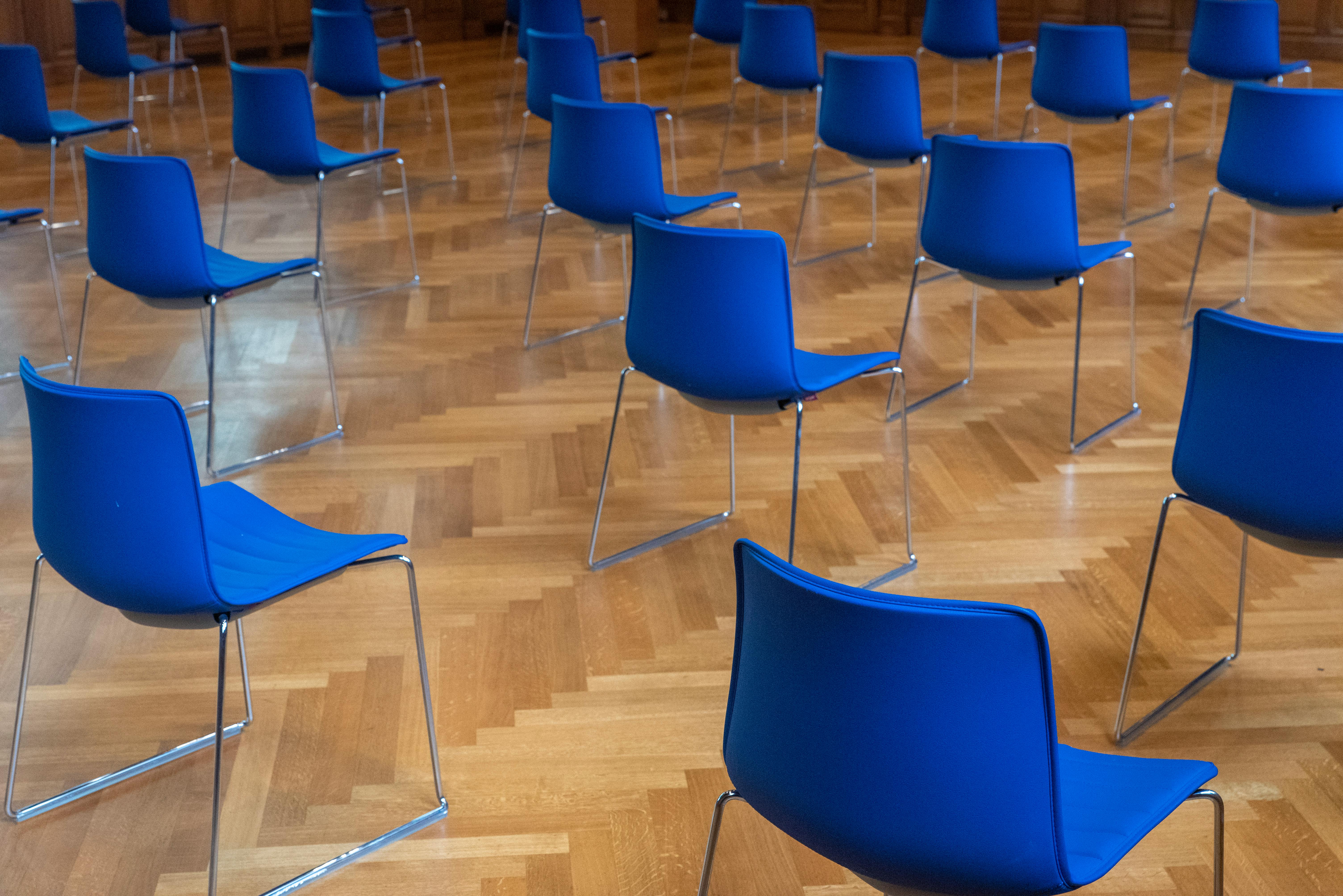 Free Empty room with blue chairs on a wooden parquet floor, arranged in rows. Stock Photo