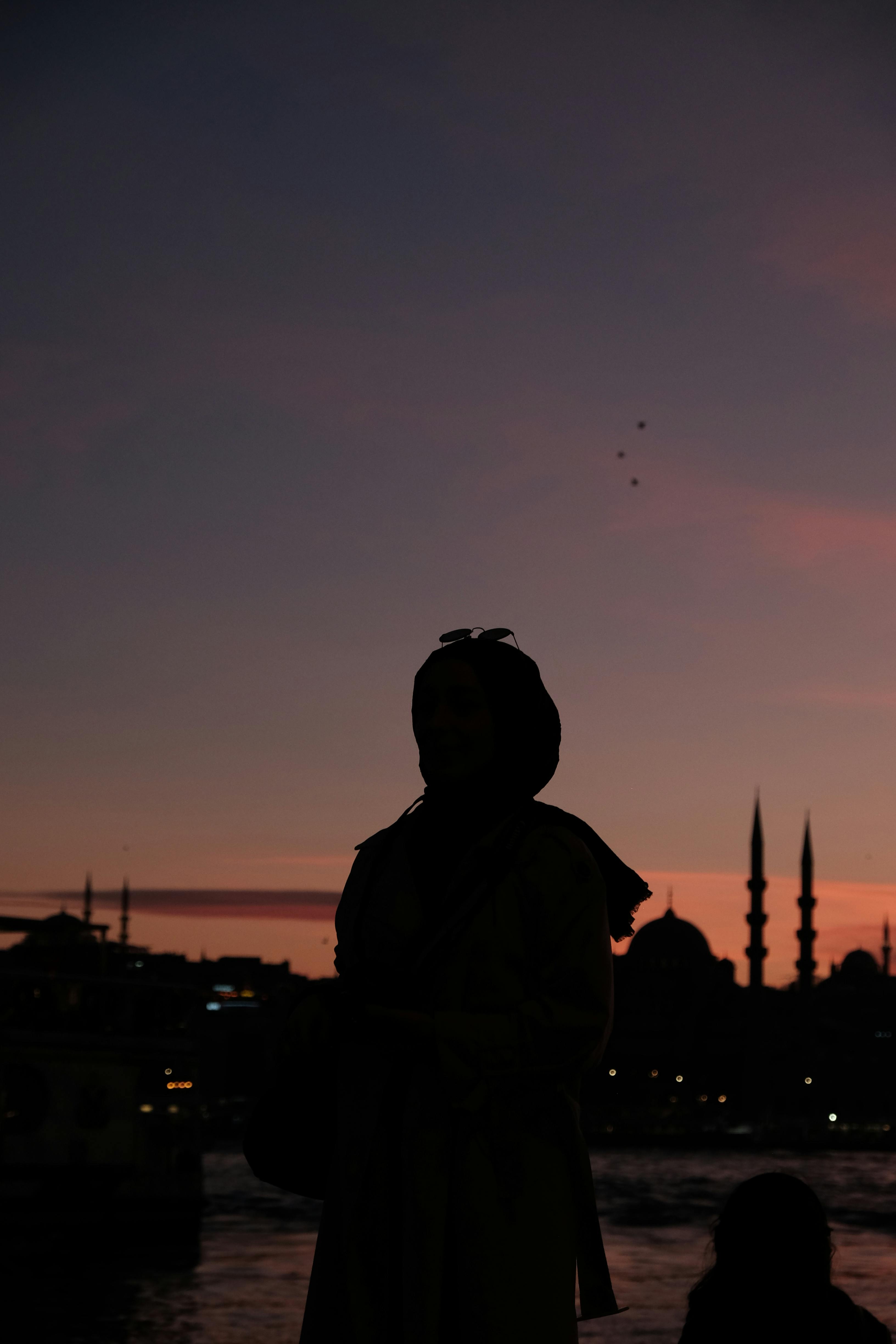 無料 トルコのイスタンブールの夕焼けのスカイラインを背景にした女性のシルエット。 写真素材