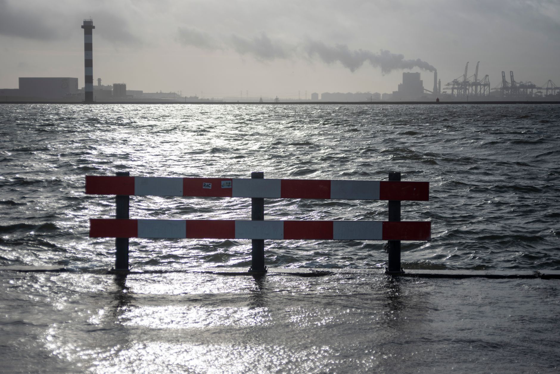 Dramatic seascape with industrial buildings and a red fence in Hoek van Holland, Nederlands.