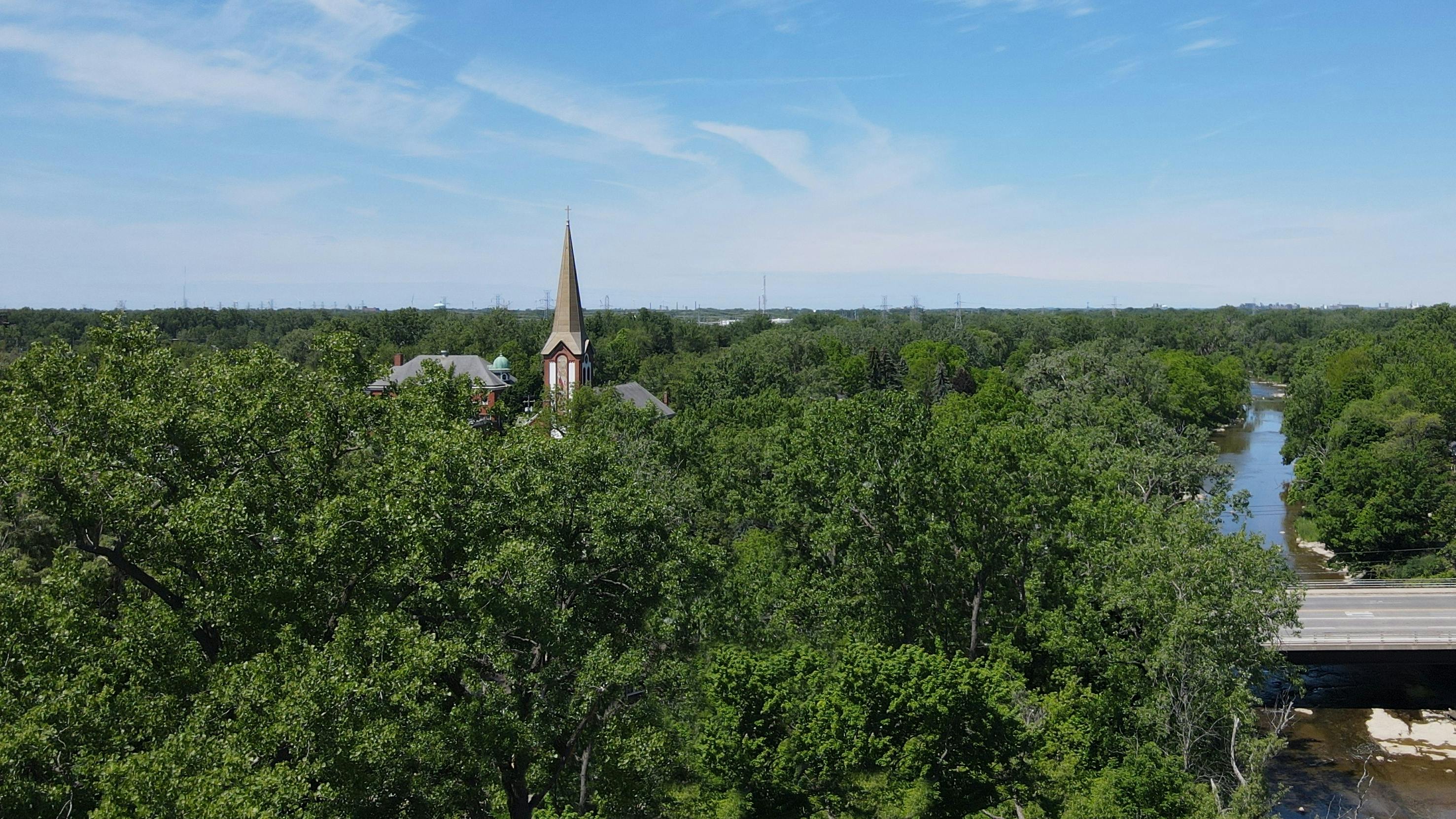 無料 明るい夏の日、川と橋のある緑豊かな森の中にある教会の尖塔。 写真素材