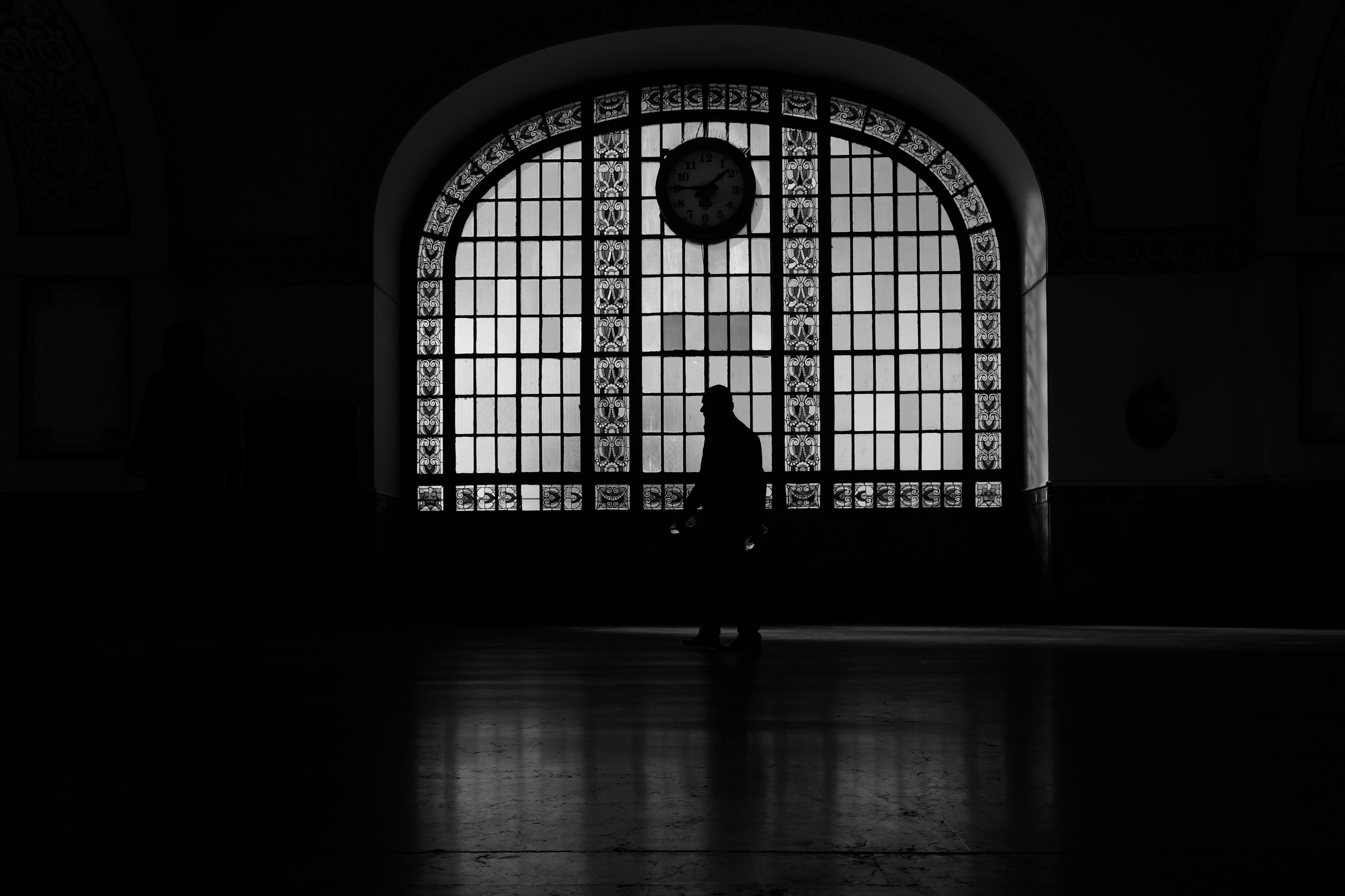 Ücretsiz İstanbul Sirkeci İstasyonu'nun içindeki kasvetli silüet, eski bir saat ve kemerli pencereyle dikkat çekiyor. Stok Fotoğraflar