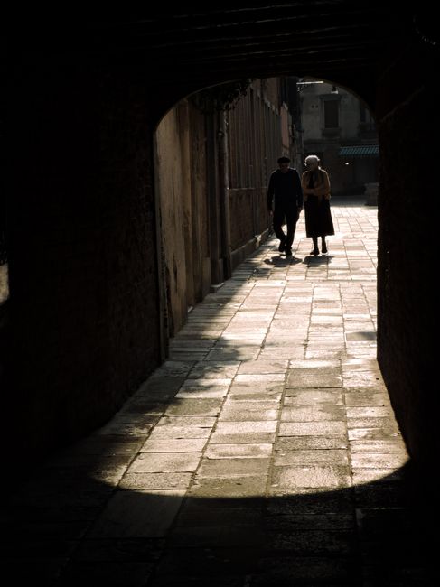 A couple's silhouette framed by a Venetian alleyway arch, capturing a timeless moment in Venice.