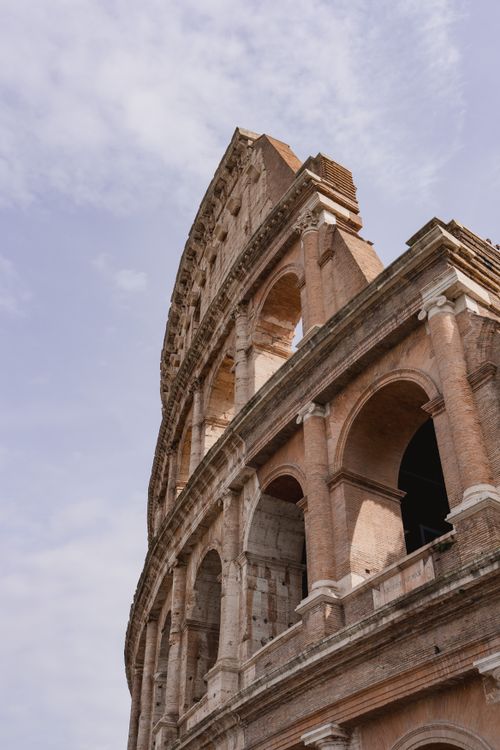 Free Close-up of the iconic Colosseum's arches under a clear blue sky in Rome, Italy. Stock Photo