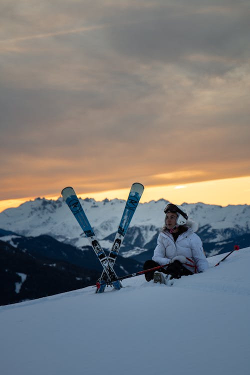 白夾克和黑褲子的人在積雪的山上騎滑雪板