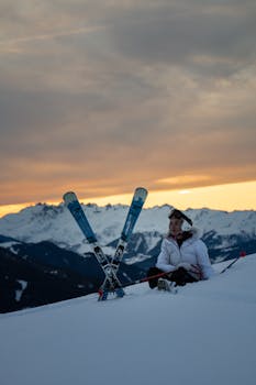 日落时分，一名滑雪者在法国布尔格圣莫里斯的雪山峰顶放松