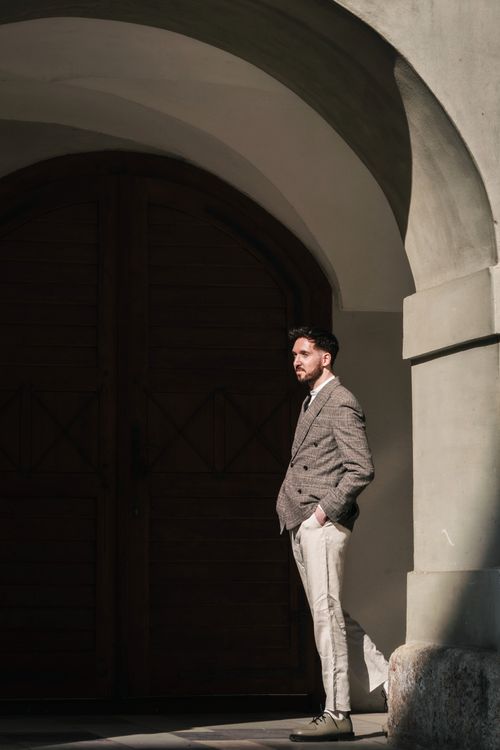 Free A fashionable man stands contemplatively beside a rustic doorway in Graz, Austria. Stock Photo