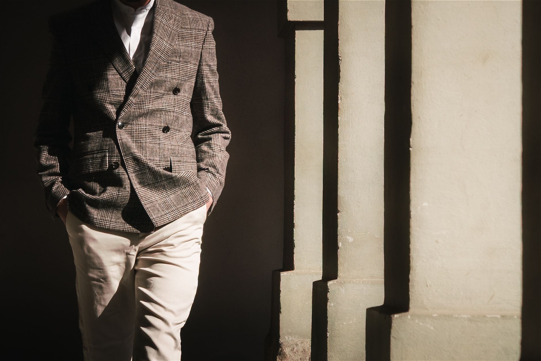 Sophisticated men's fashion with a plaid blazer and khakis, captured in striking sunlight and shadows.