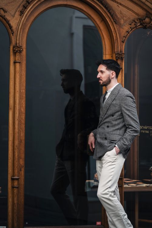 Free Adult male in sleek suit with urban flair, posing outside a vintage window in Graz, Austria. Stock Photo